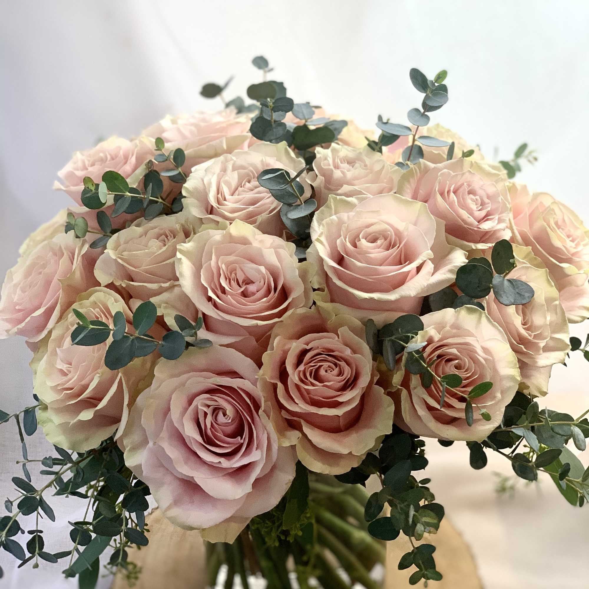 Blush pink roses and eucalyptus in a clear vase. 