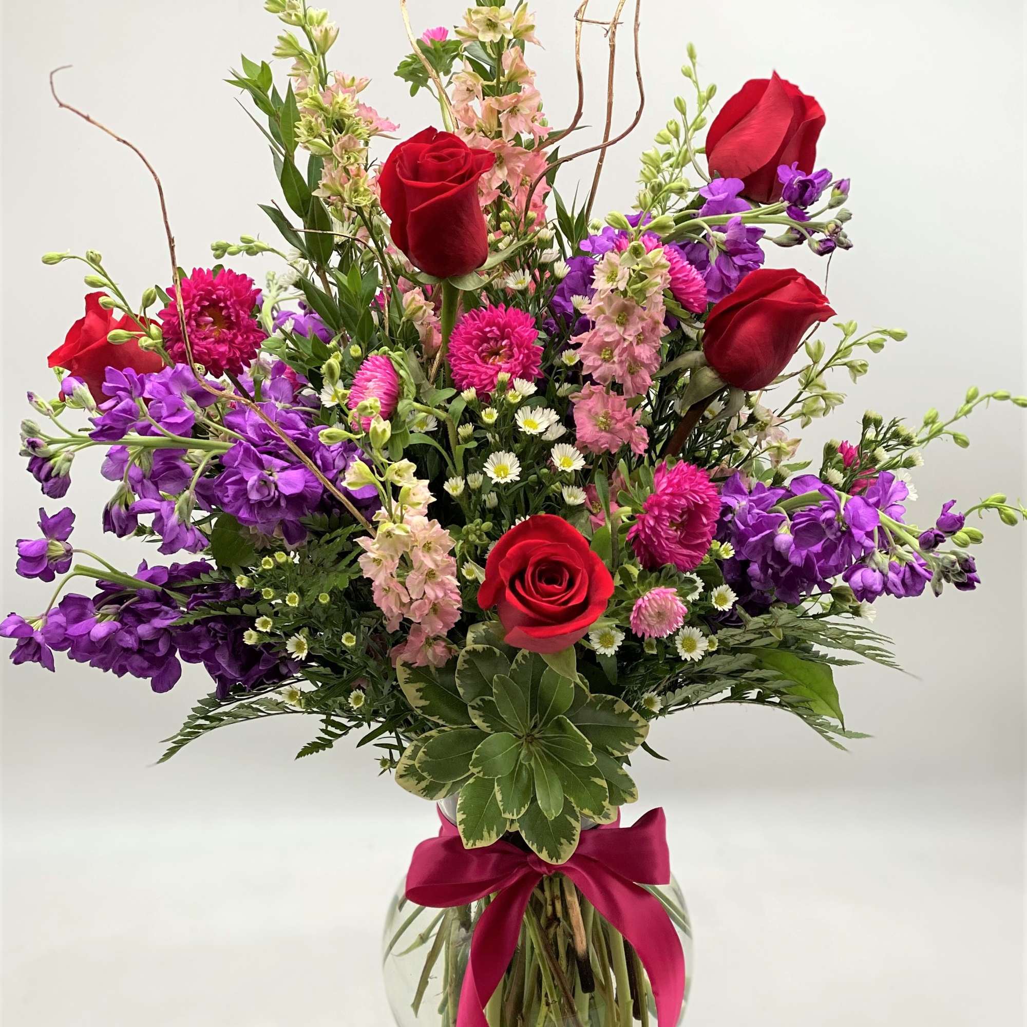 A beautiful mix of roses, stock, larkspur and more in a clear