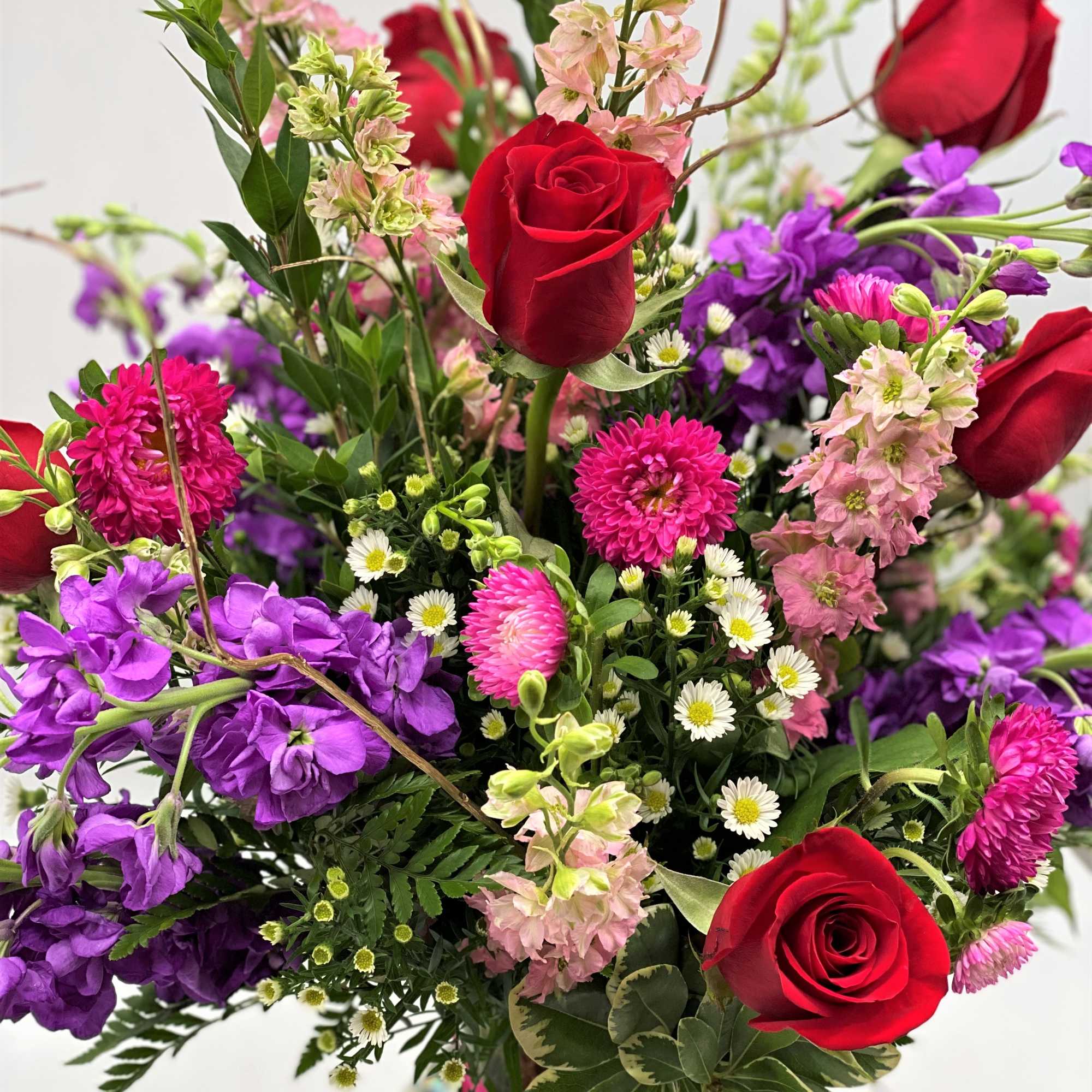 A beautiful mix of roses, stock, larkspur and more in a clear