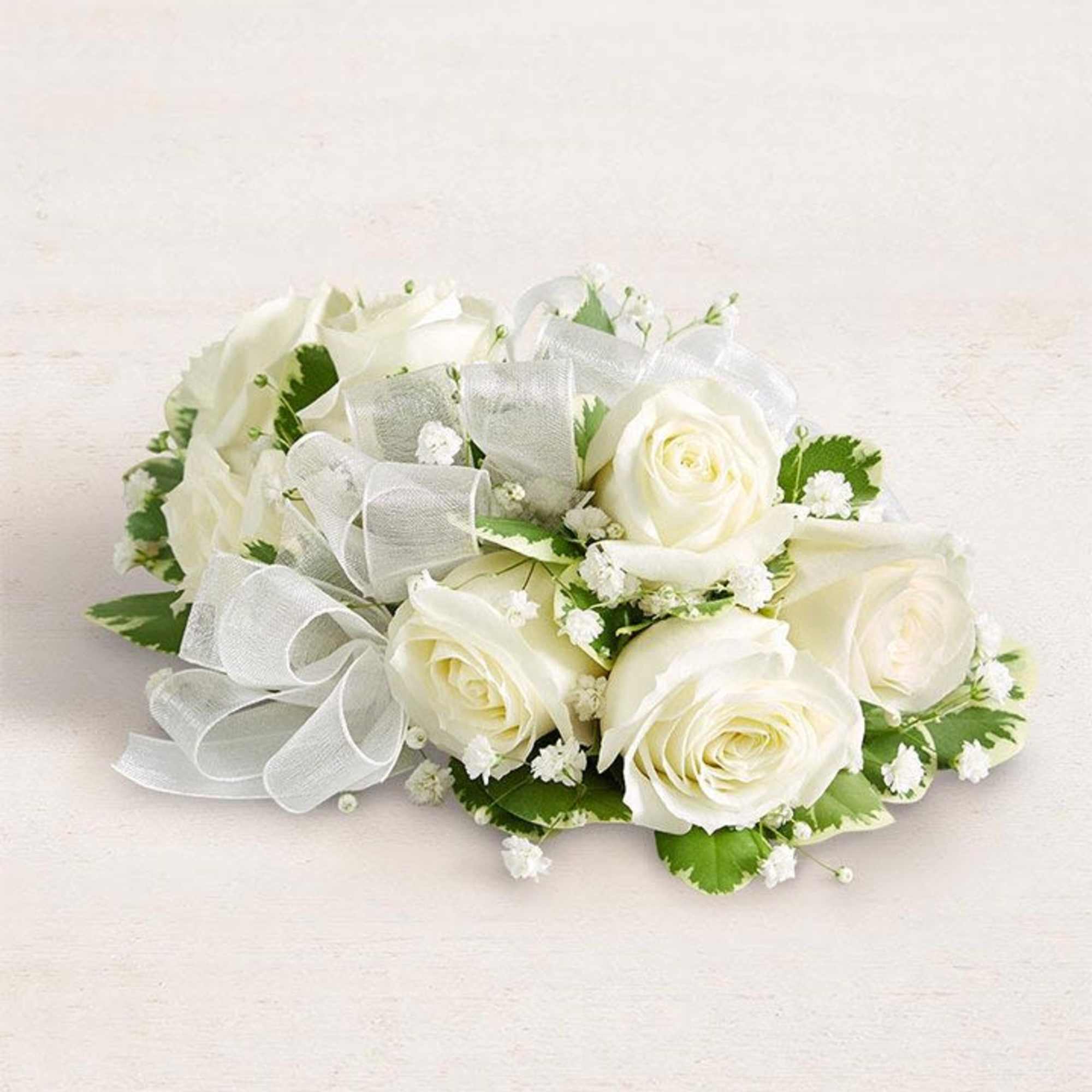 A stunning, handcrafted corsage featuring elegant white roses and fresh greenery accents