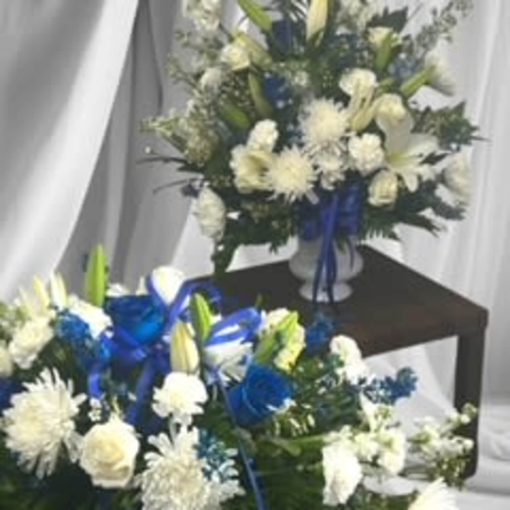 White lilies white roses and white stock encapsulated in greens and accented