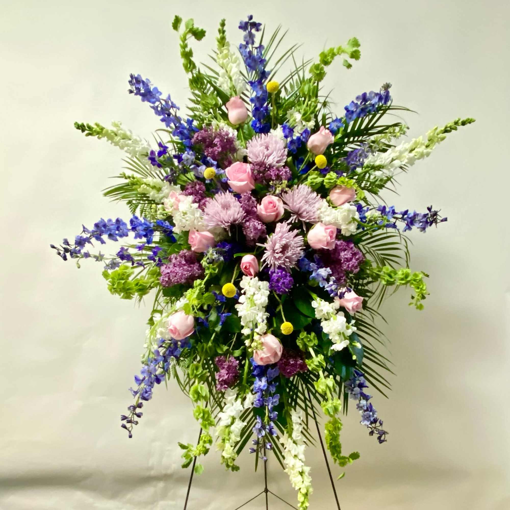 The Standing Spray on an Easel includes Blue Delphinium, Lavender Fuji Mums