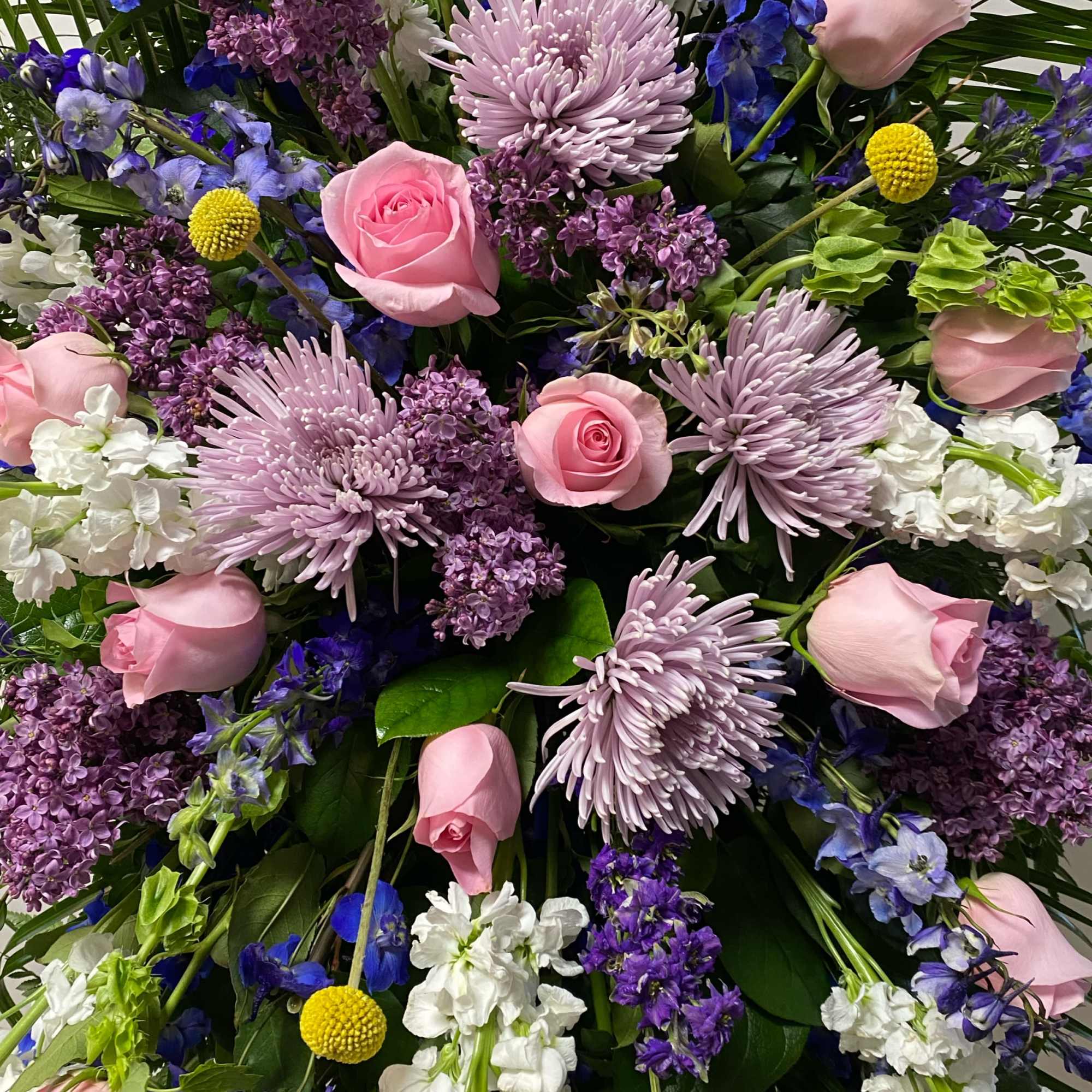 The Standing Spray on an Easel includes Blue Delphinium, Lavender Fuji Mums