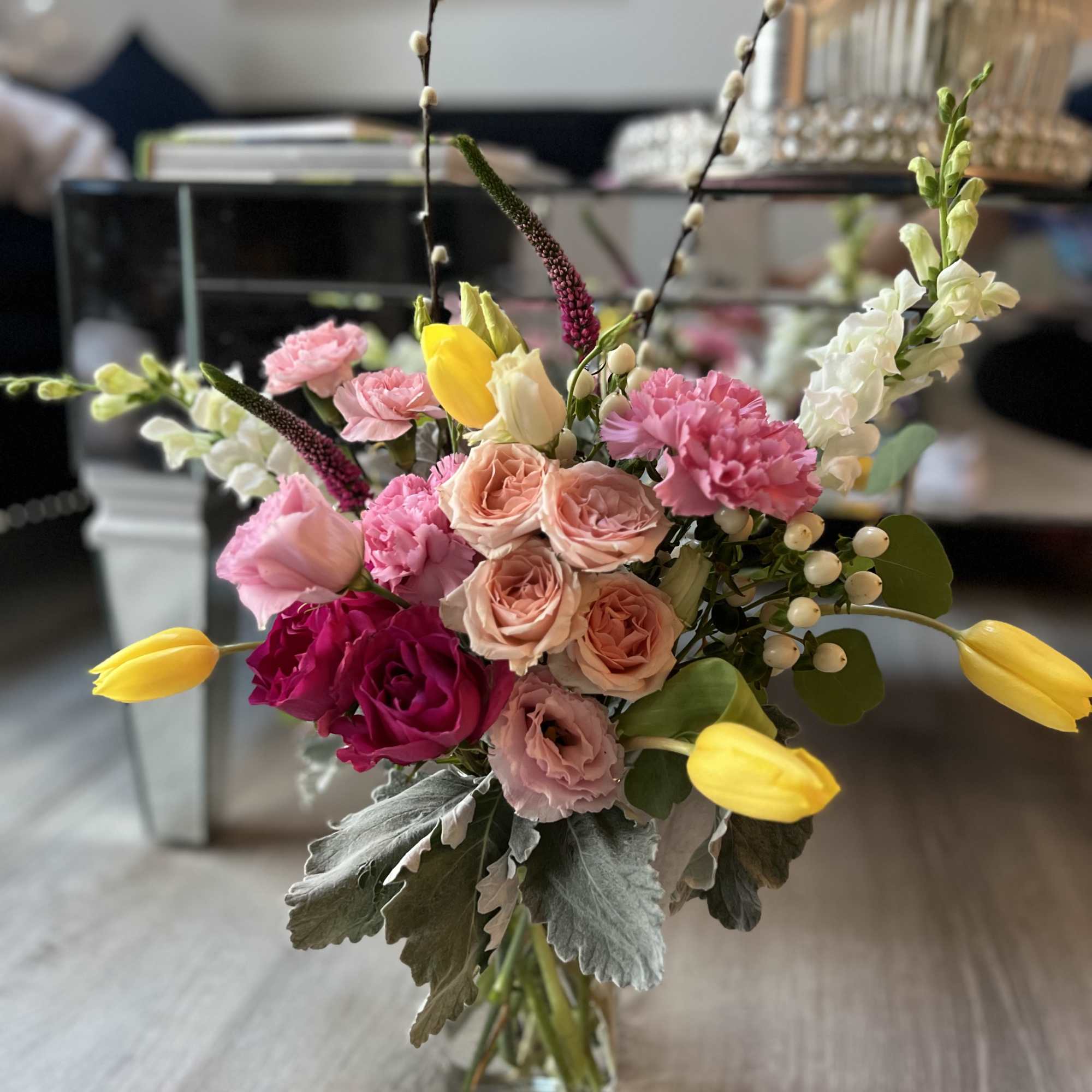 A bouquet made of pink spray roses, yellow tulips, white stock, and