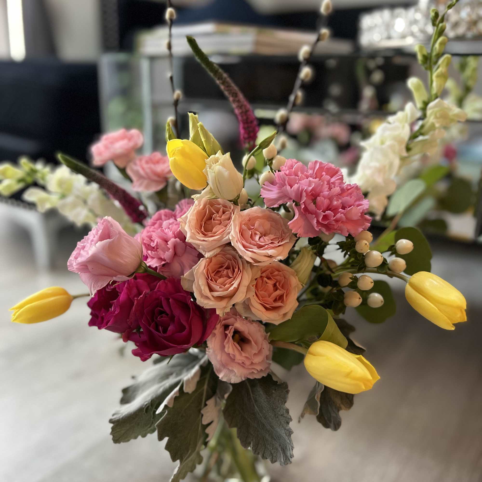 A bouquet made of pink spray roses, yellow tulips, white stock, and