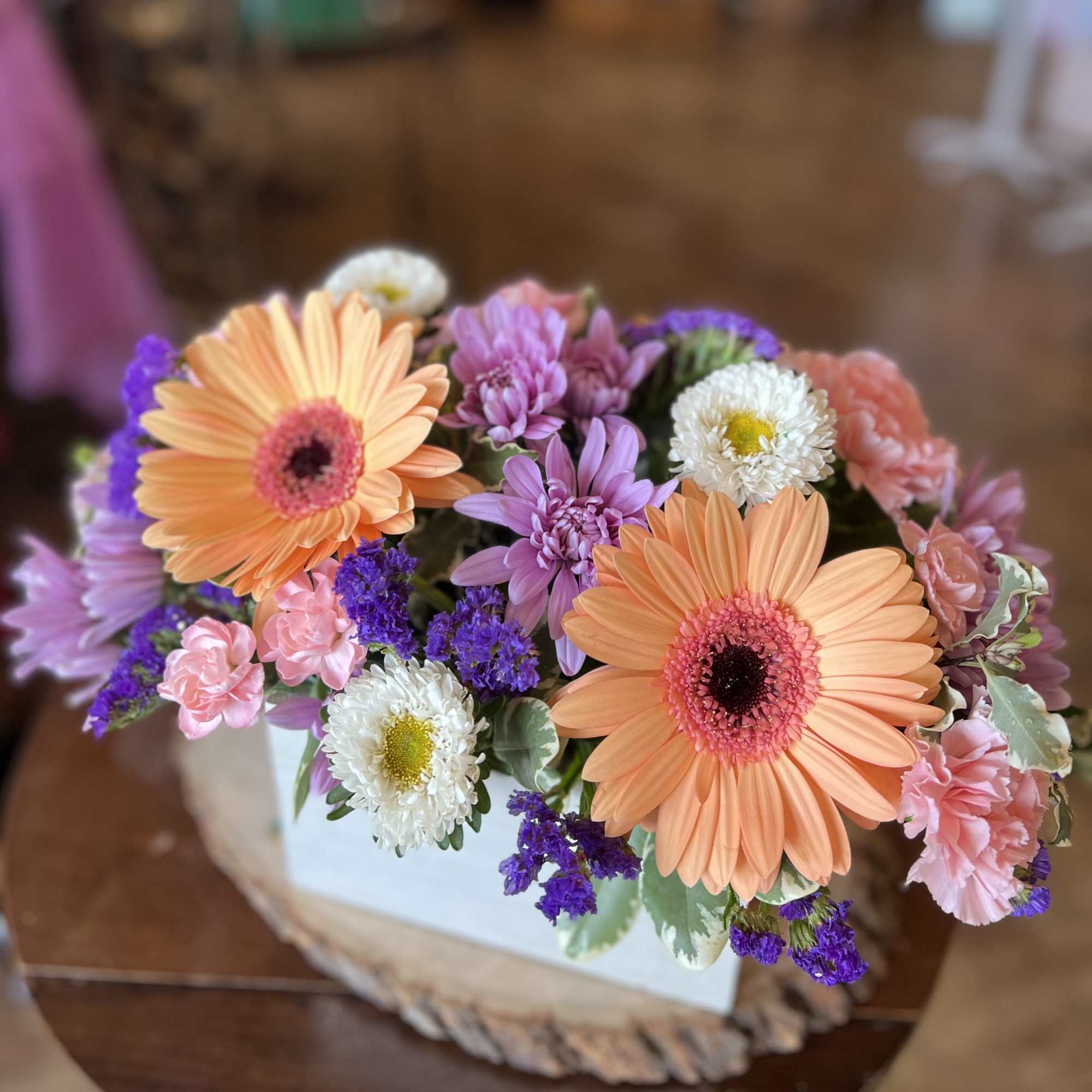This uplifting box arrangement contains gerber daisy&rsquo;s, statice, cushion poms, asters, and
