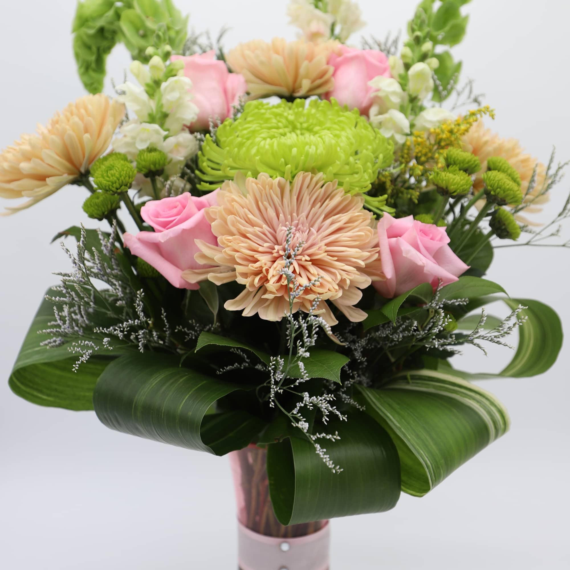 A gorgeous arrangement made with chrysanthemums, roses, button mums, snapdragons, bells of