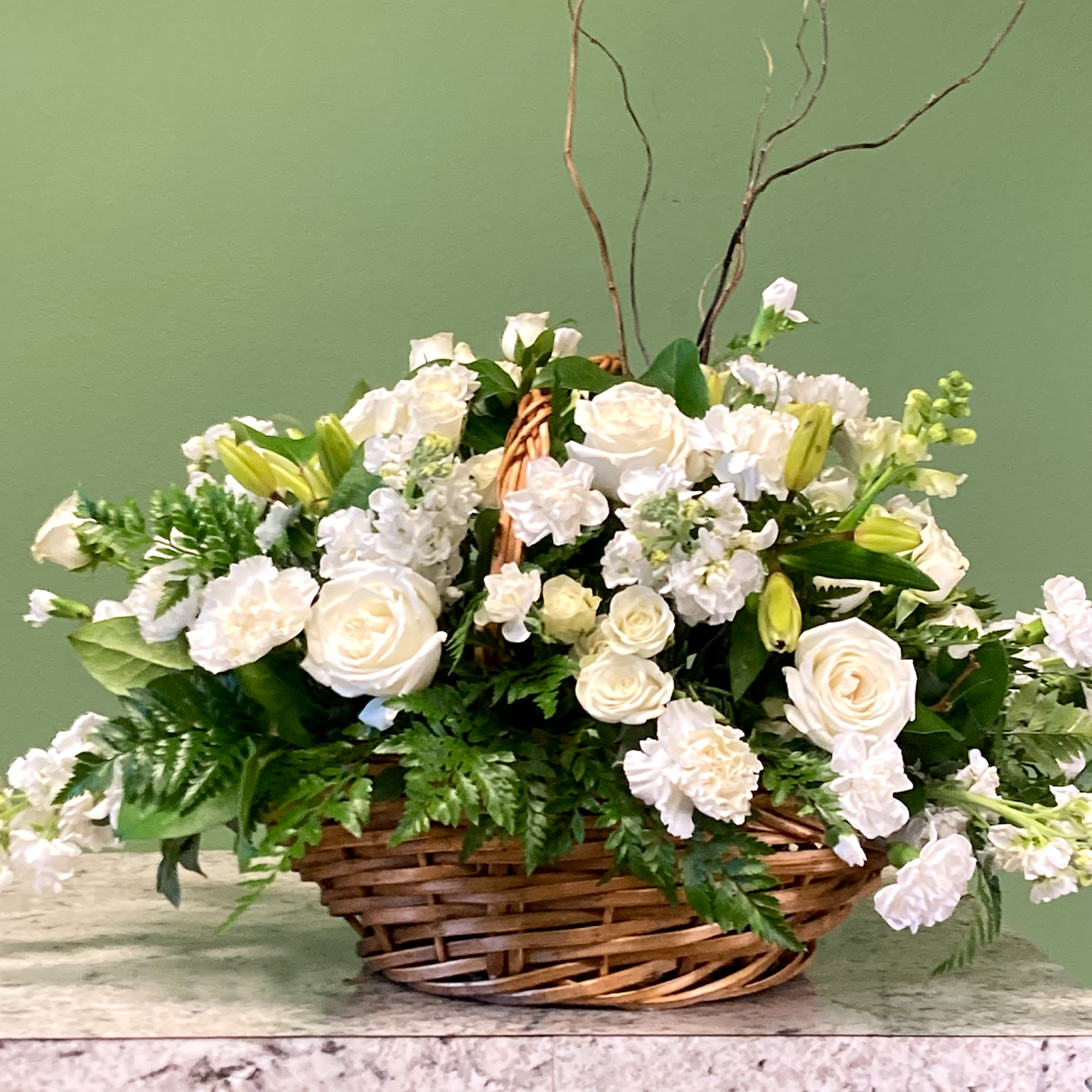 A tranquil mixed arrangement that arrives in a natural wicker basket, showcasing