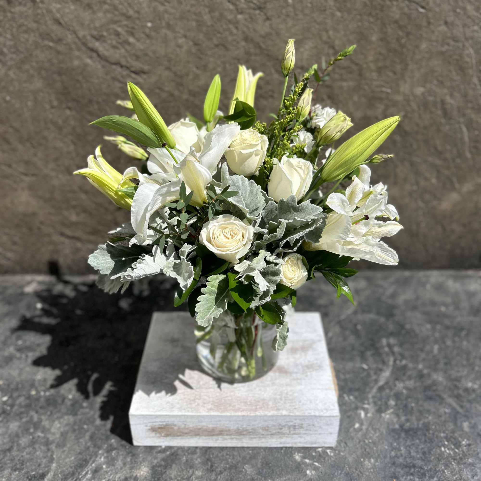 White Roses, white lilies,  lisianthus, dusty miller, eucalyptus, and other blooming