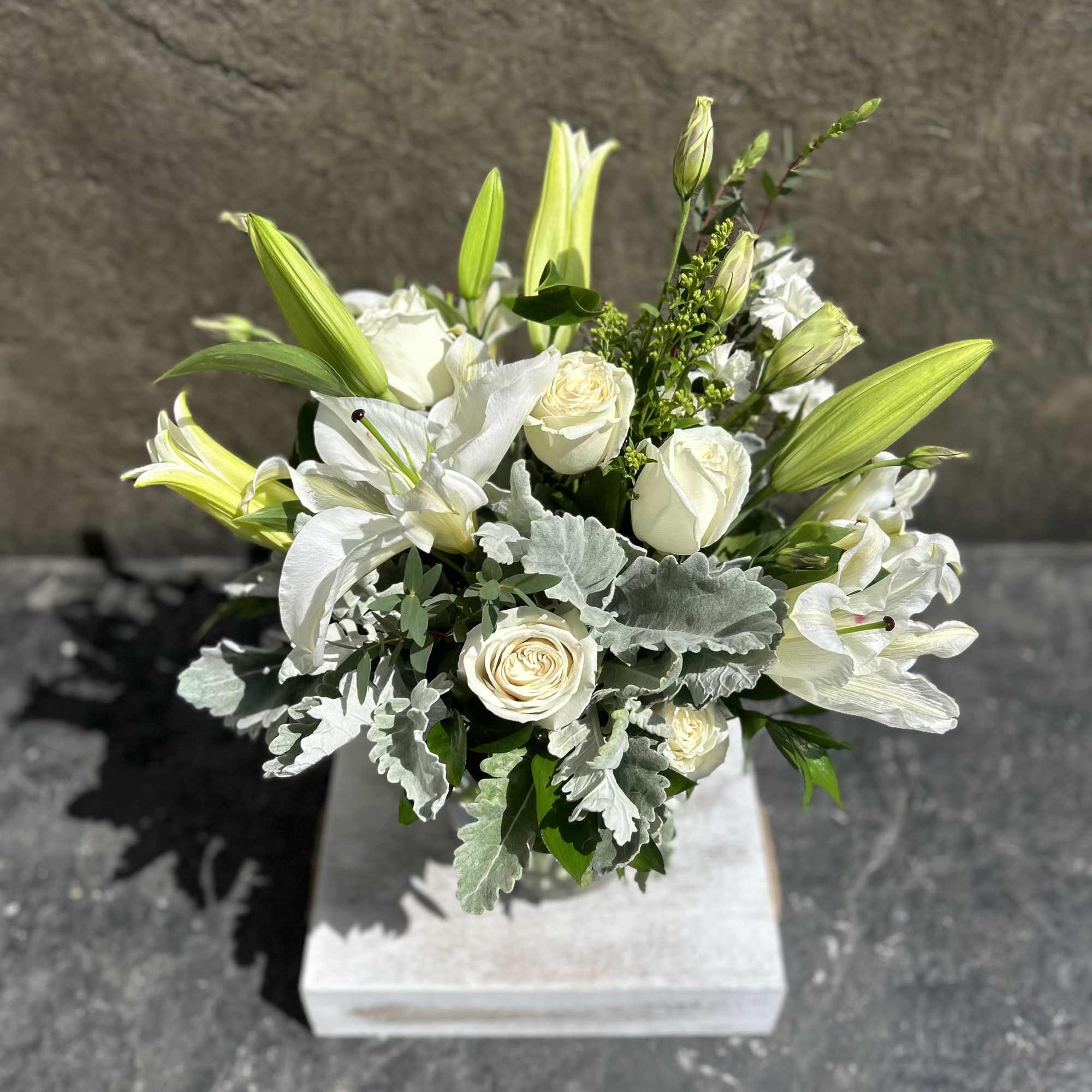 White Roses, white lilies,  lisianthus, dusty miller, eucalyptus, and other blooming
