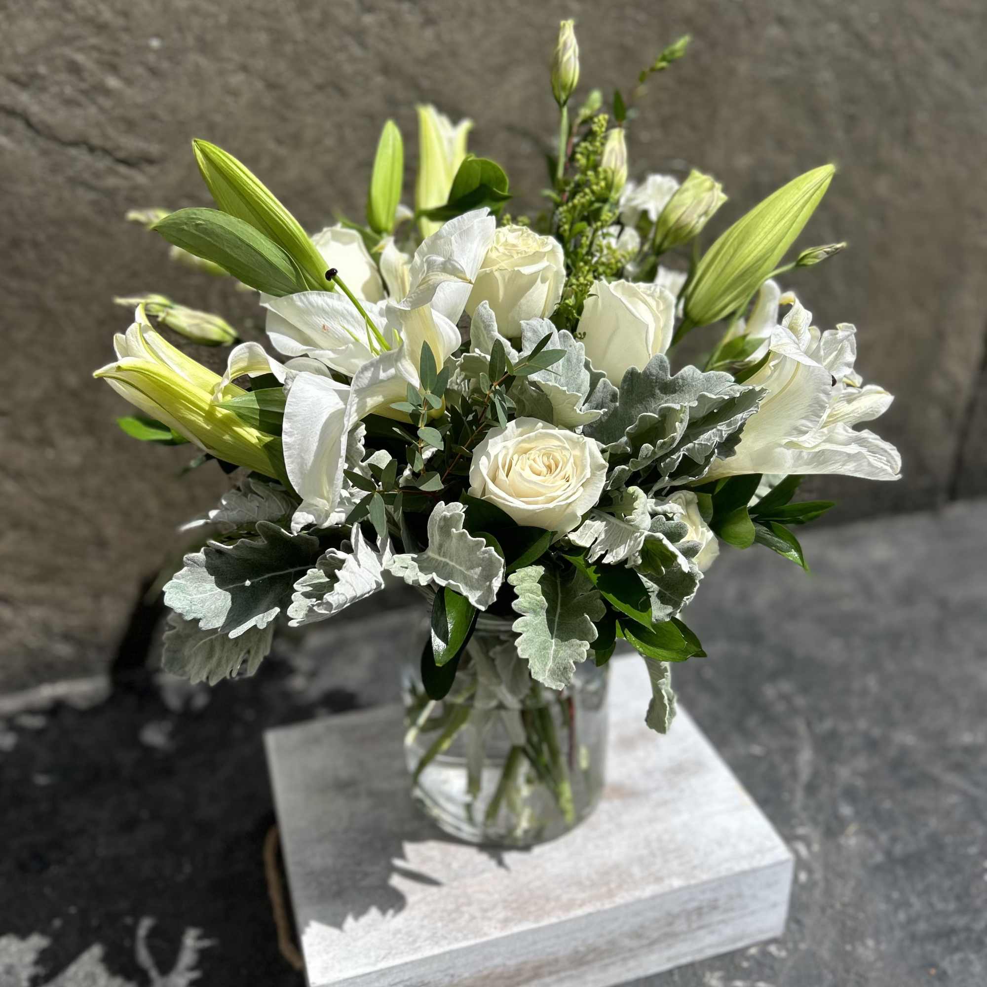White Roses, white lilies,  lisianthus, dusty miller, eucalyptus, and other blooming