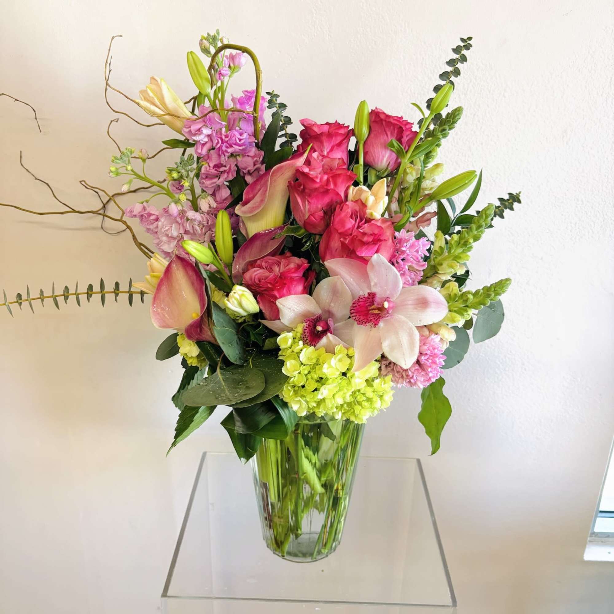 A tropical arrangement filled with tropical florals like cymbidium orchids, fresh pinks