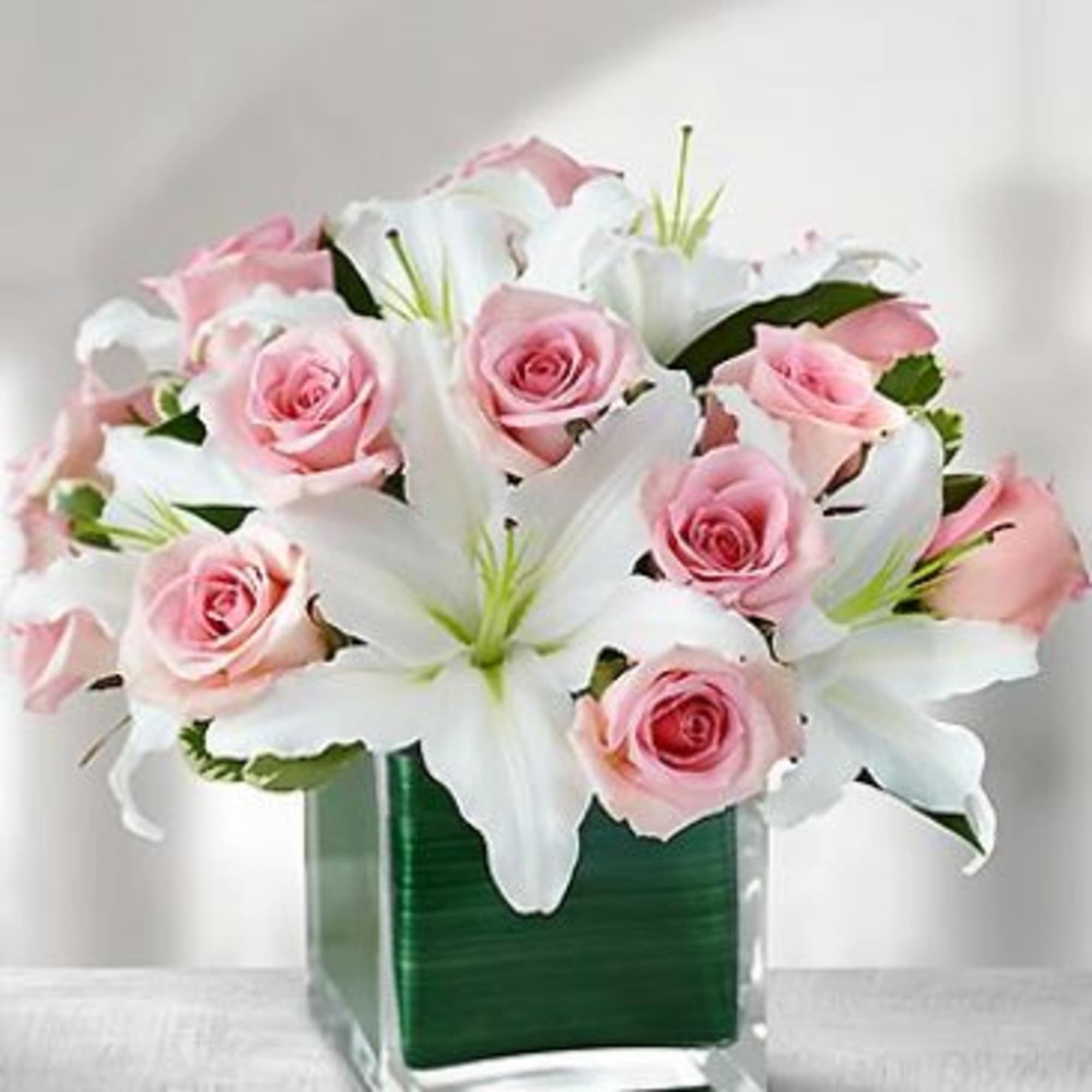 White Lilies and 12 Pink Roses with greens arranged in a glass White Lilies and 12 Pink Roses with greens arranged in a glass