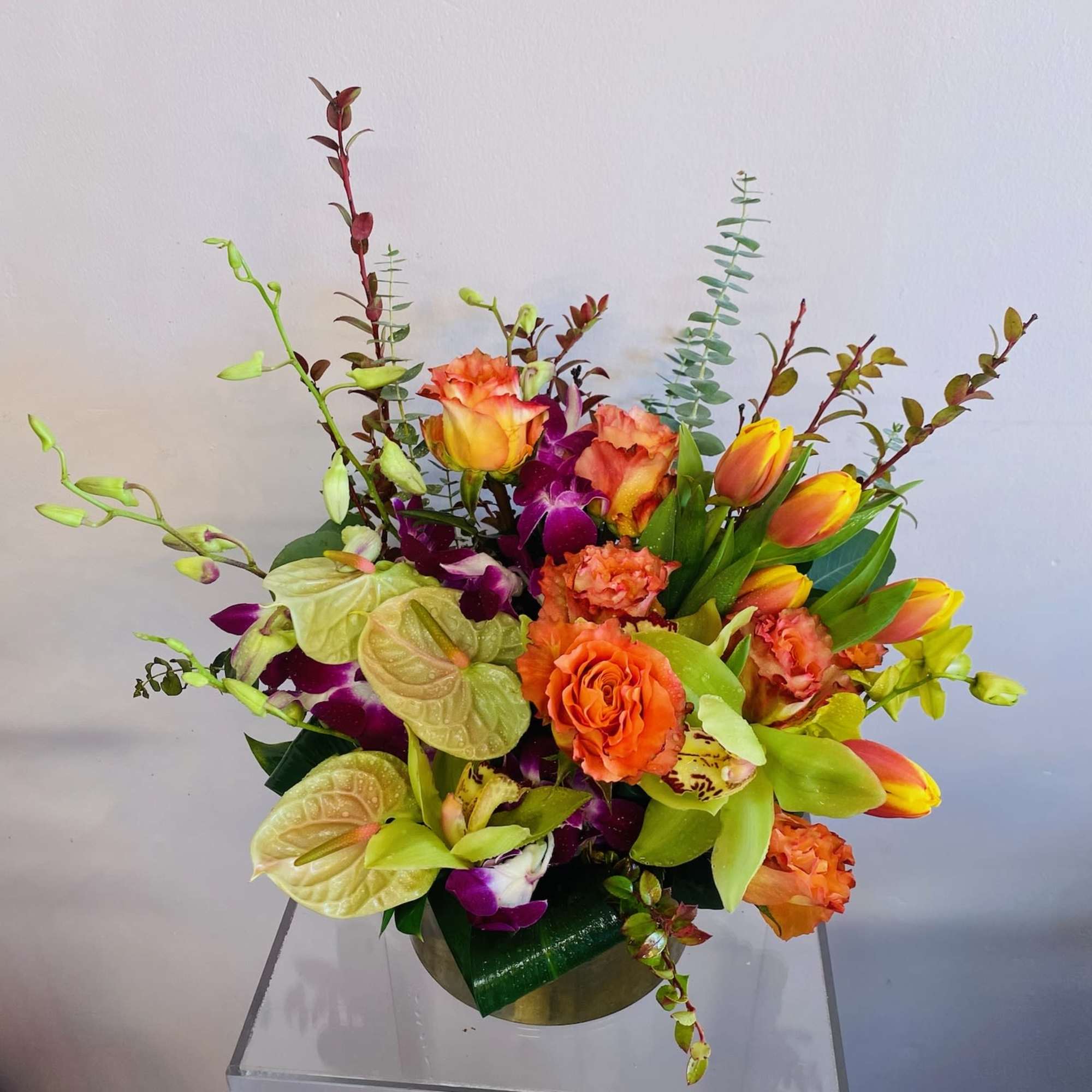 Green anthurium, orange tulips, orange crush roses, pink bom dendrobium orchids accent