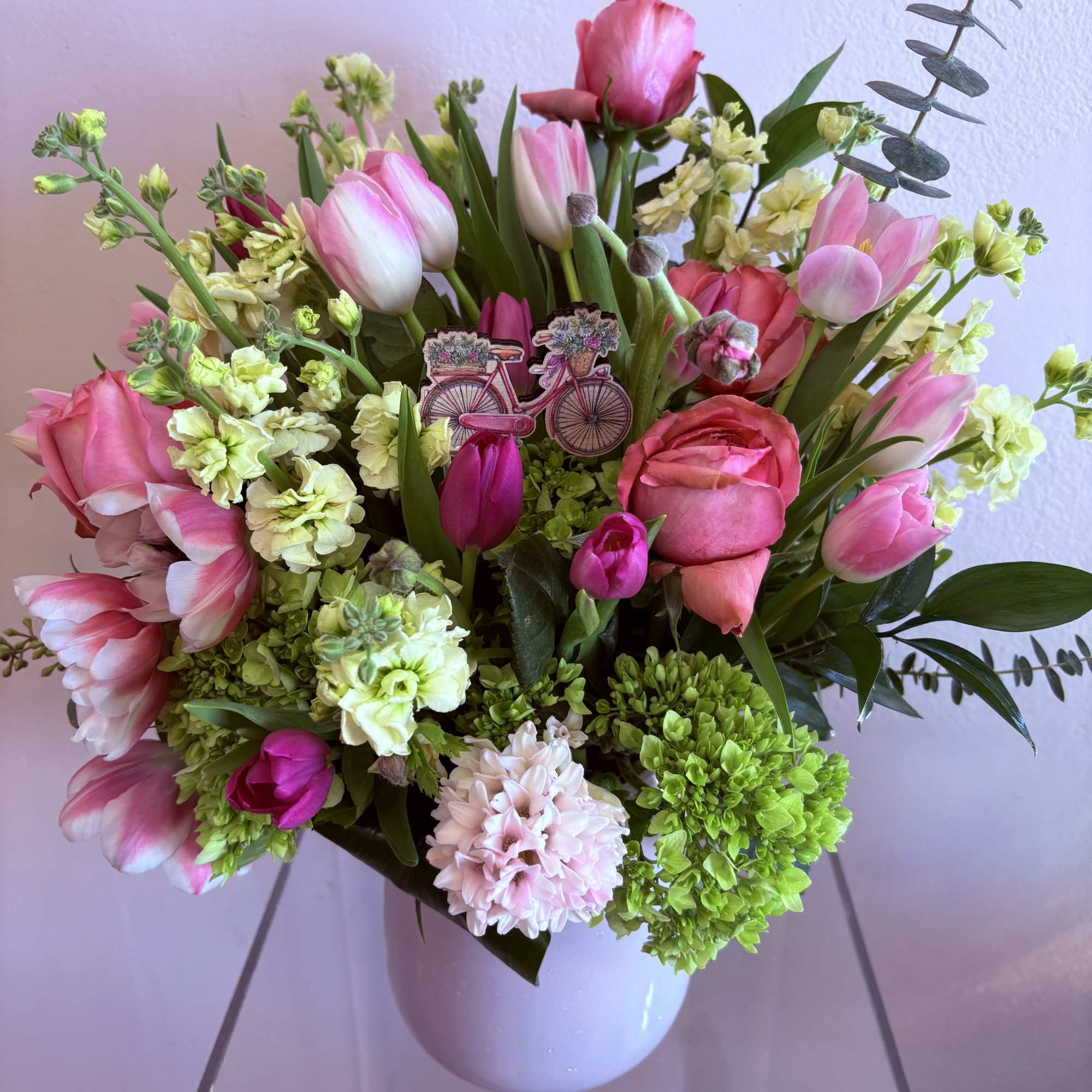 Pink tulips, pink garden roses, yellow stock, green hydrangeas and hyacinth.