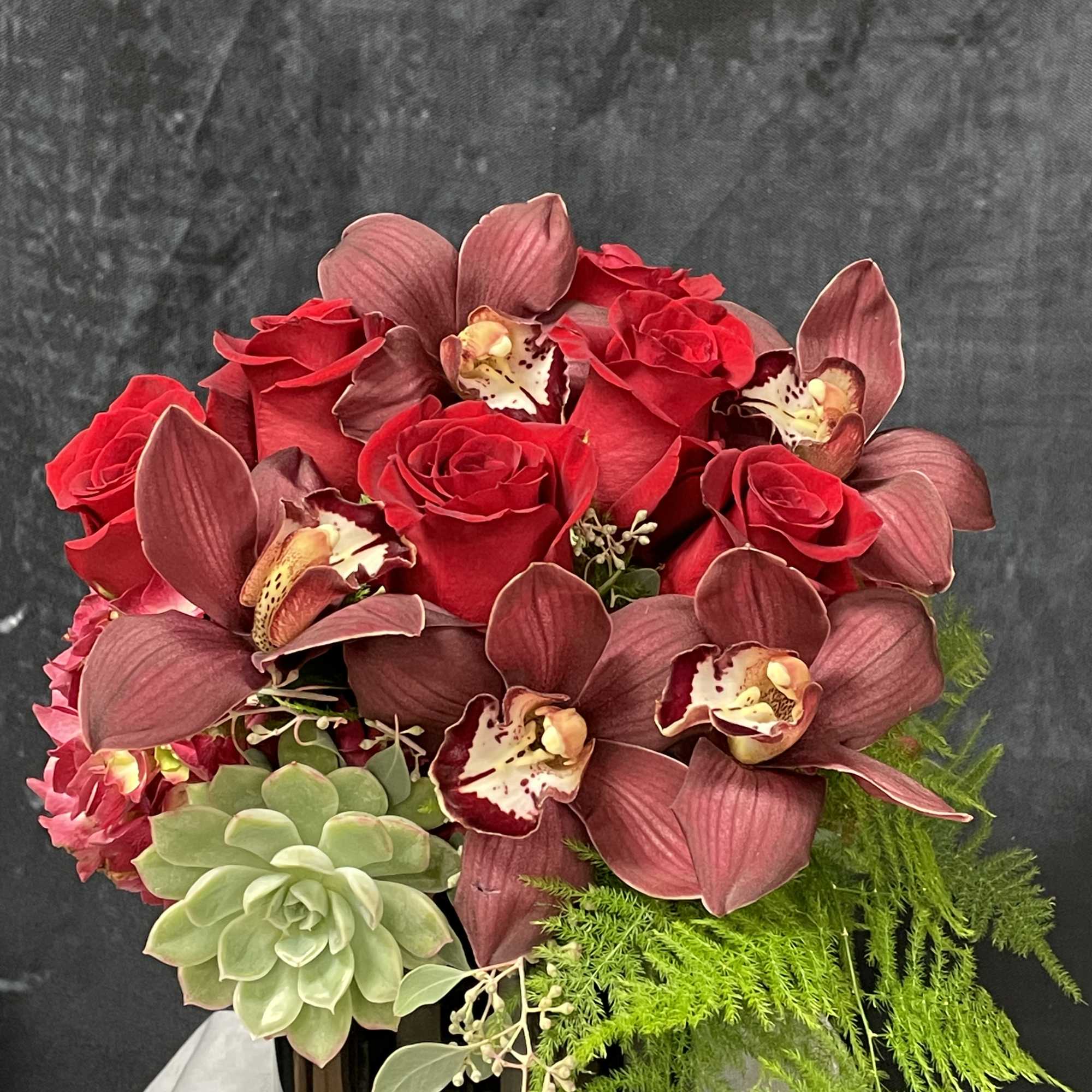 Natural red hydrangeas, red roses, burgundy cymbidiums, succulent and greenery in a Natural red hydrangeas, red roses, burgundy cymbidiums, succulent and greenery in a