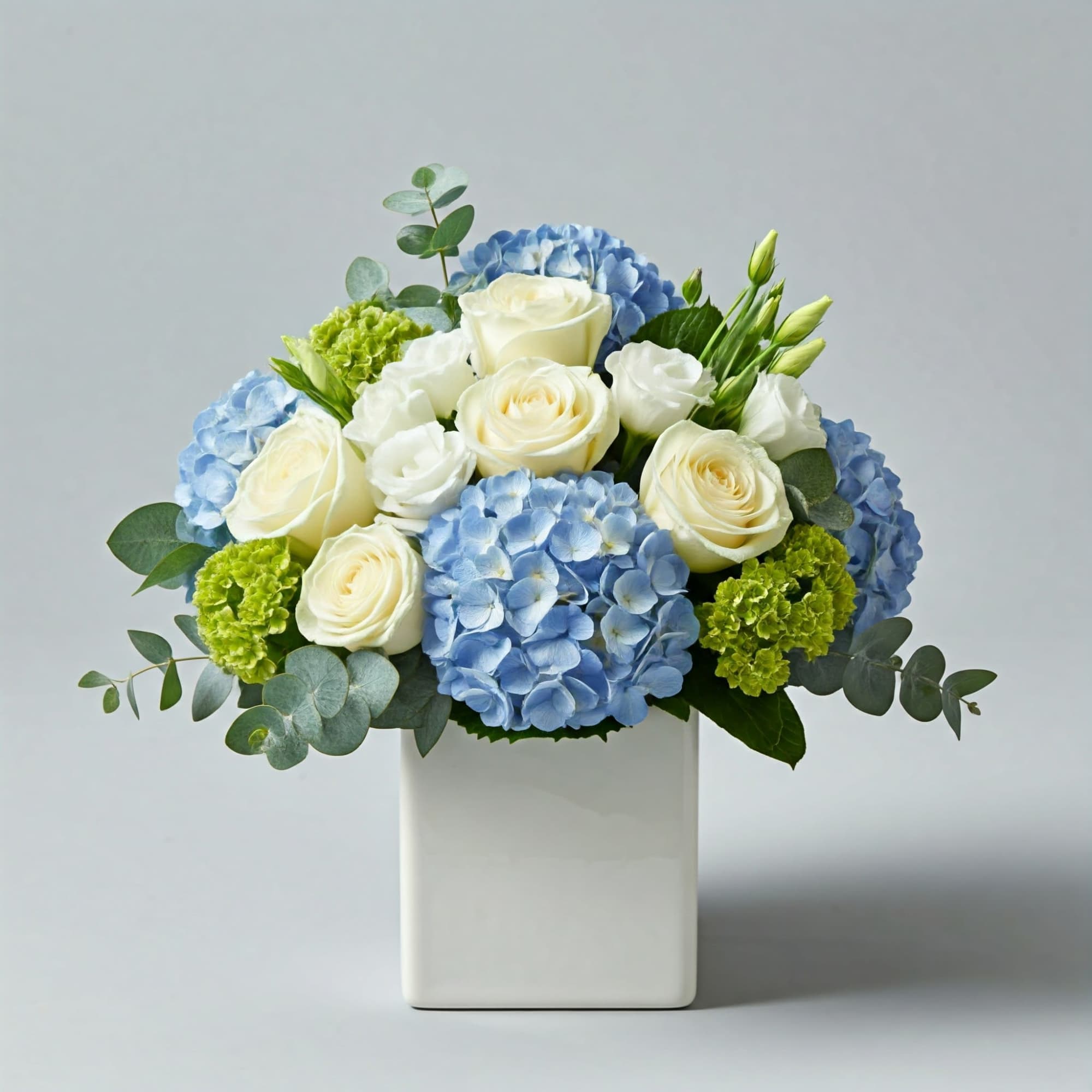 A fluffy floral bouquet in a chic white ceramic container. Featuring our