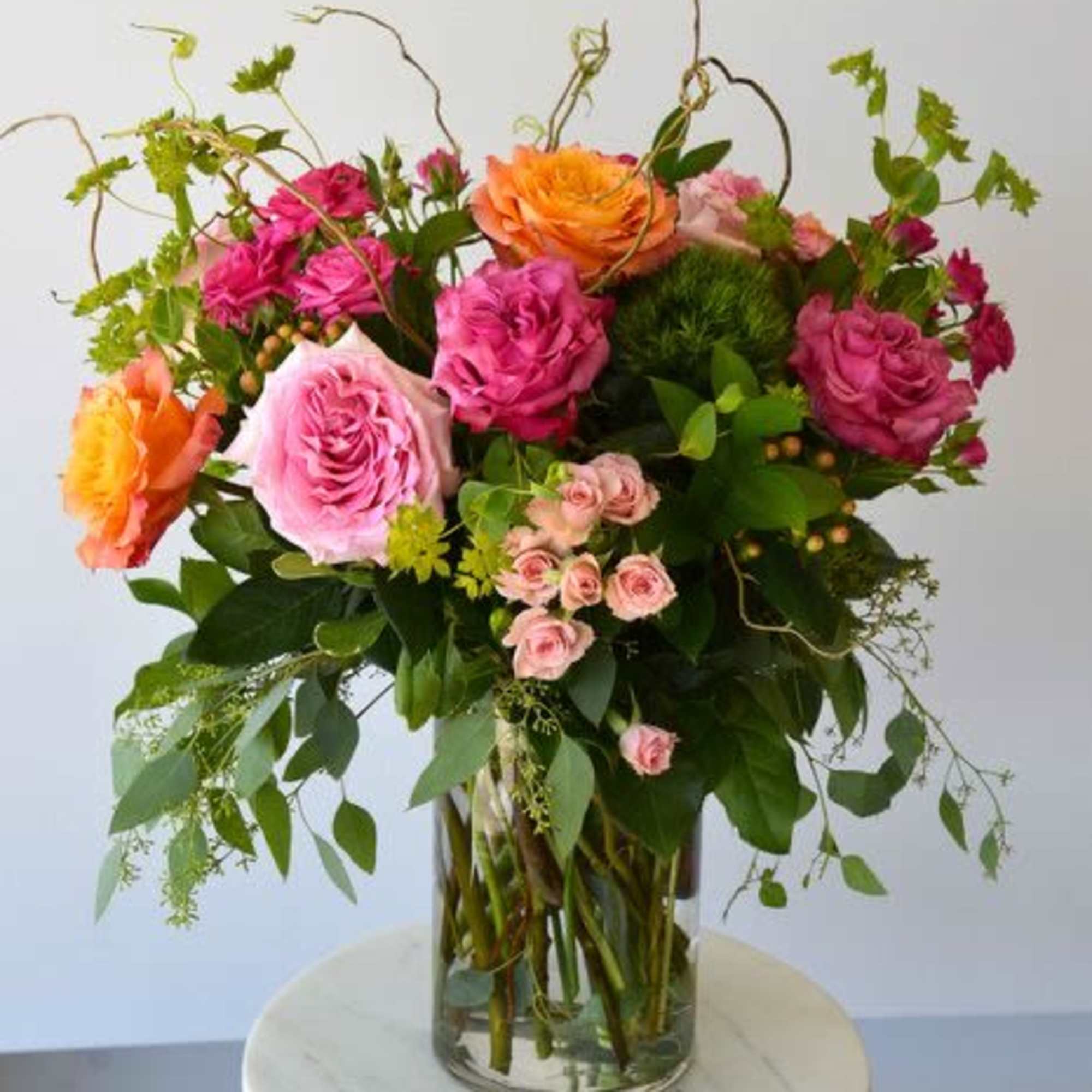This untamed beauty features brightly colored roses and playful greens, evoking the