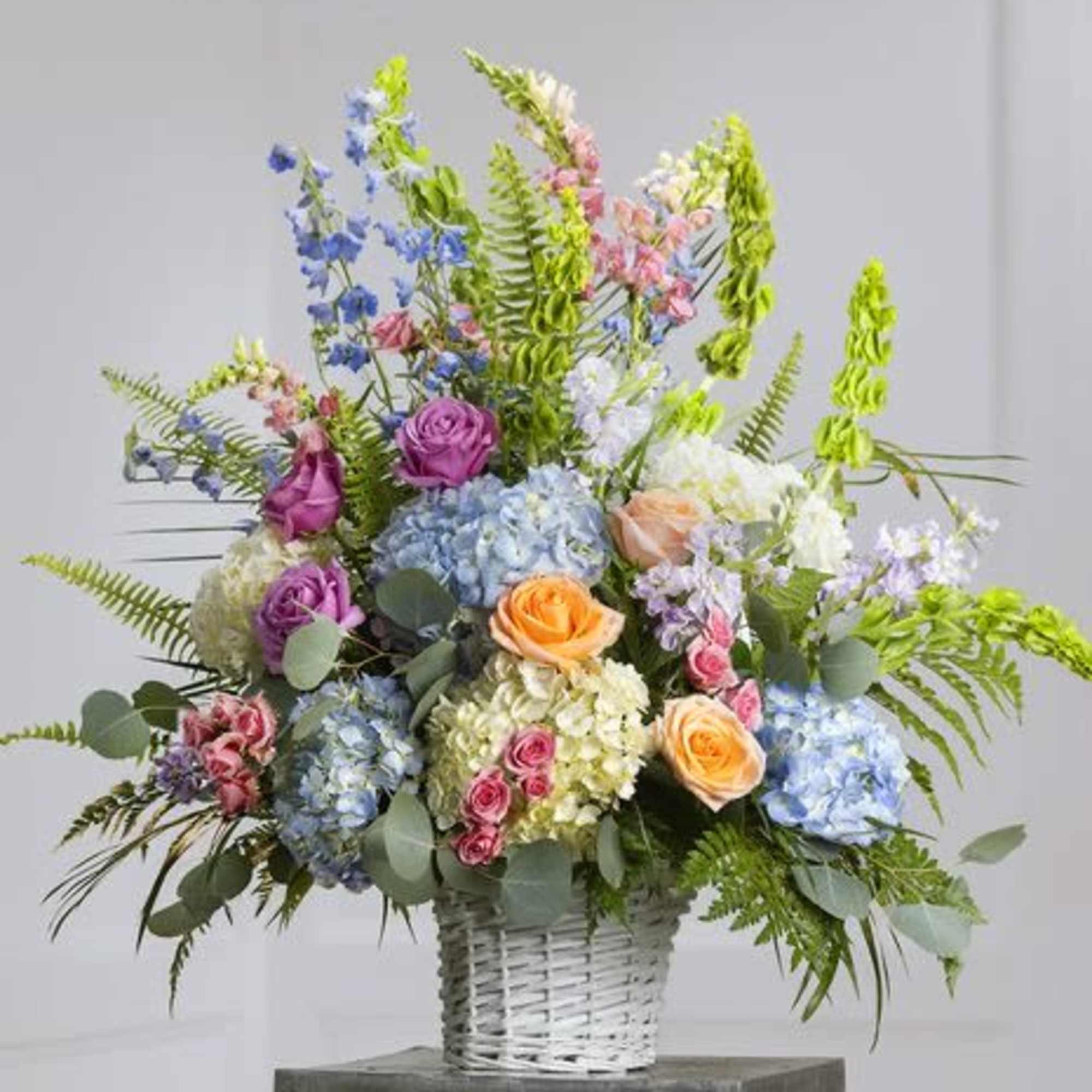 A graceful spring-inspired basket featuring soft hydrangeas, roses, lisianthus, and bells of