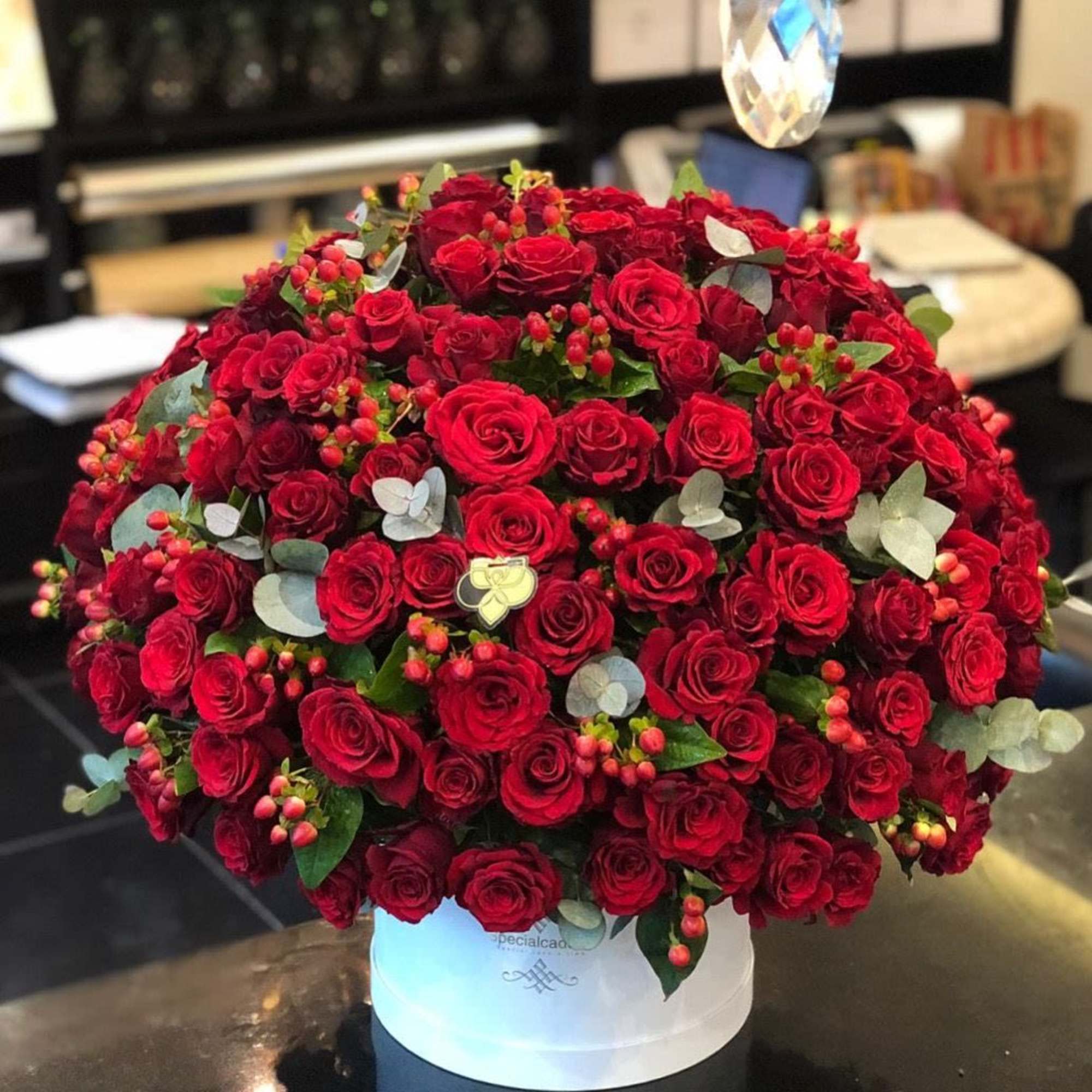 &ldquo;A lavish arrangement of deep red roses, accented with eucalyptus and berries