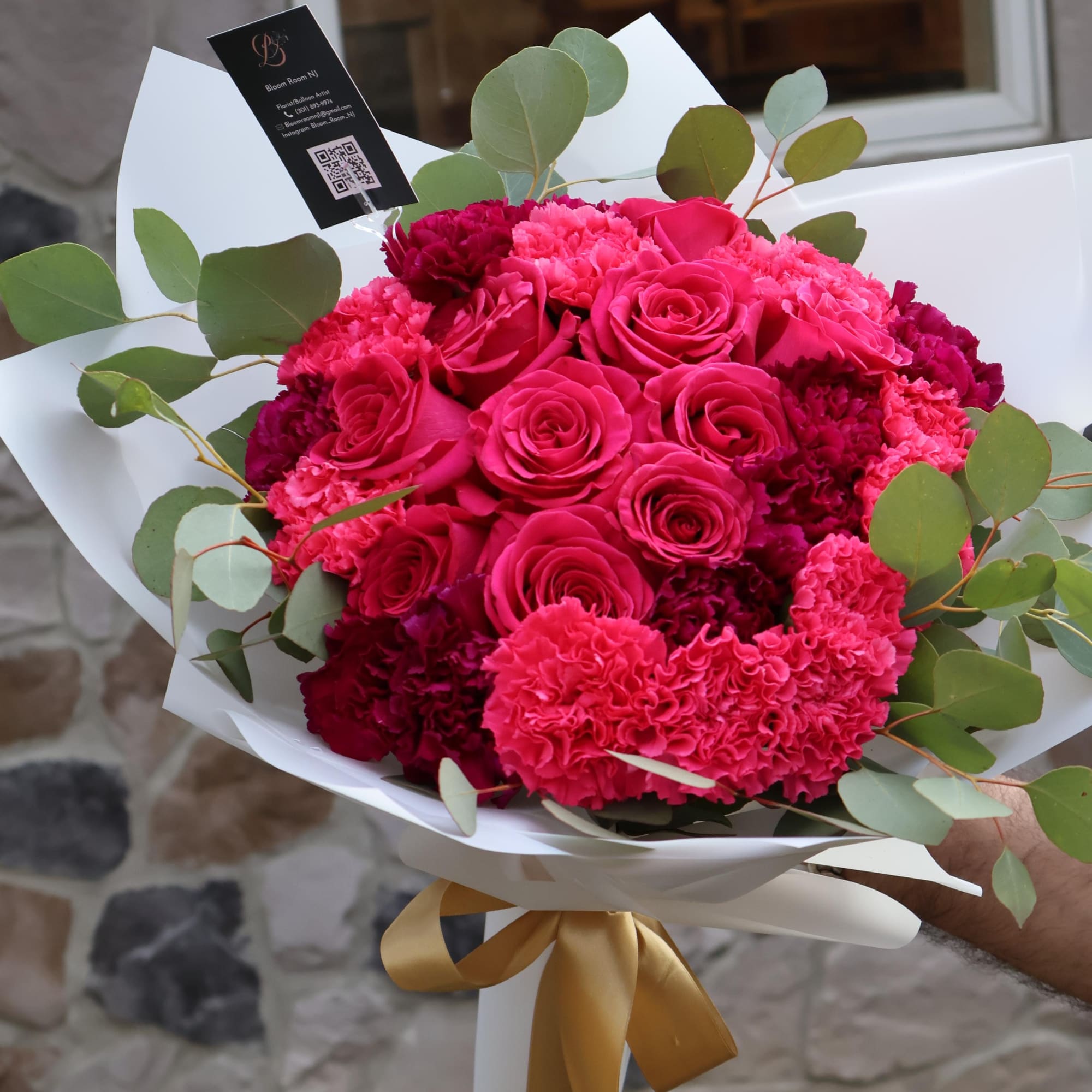 A striking fusion of hot pink roses and deep purple carnations, wrapped