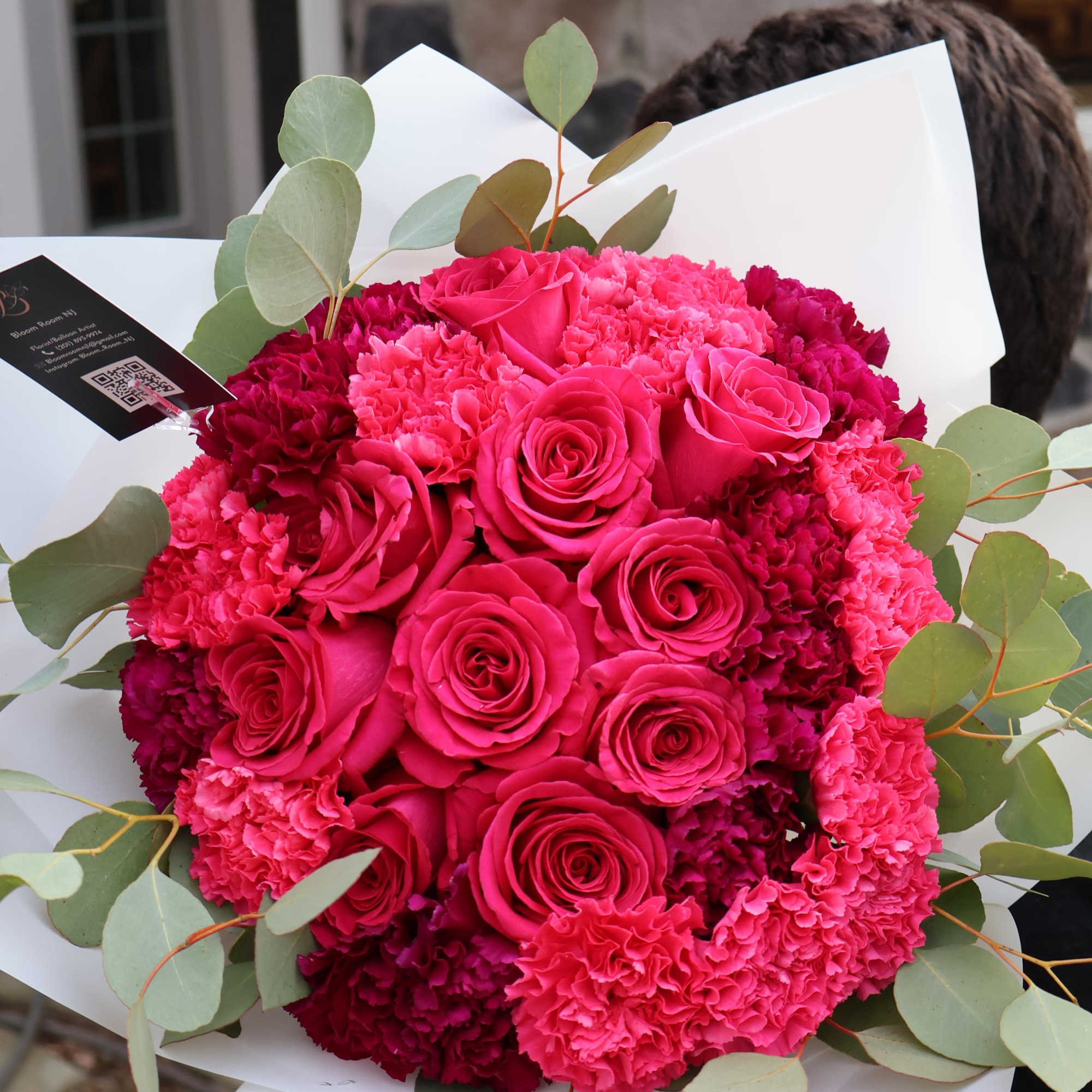 A striking fusion of hot pink roses and deep purple carnations, wrapped
