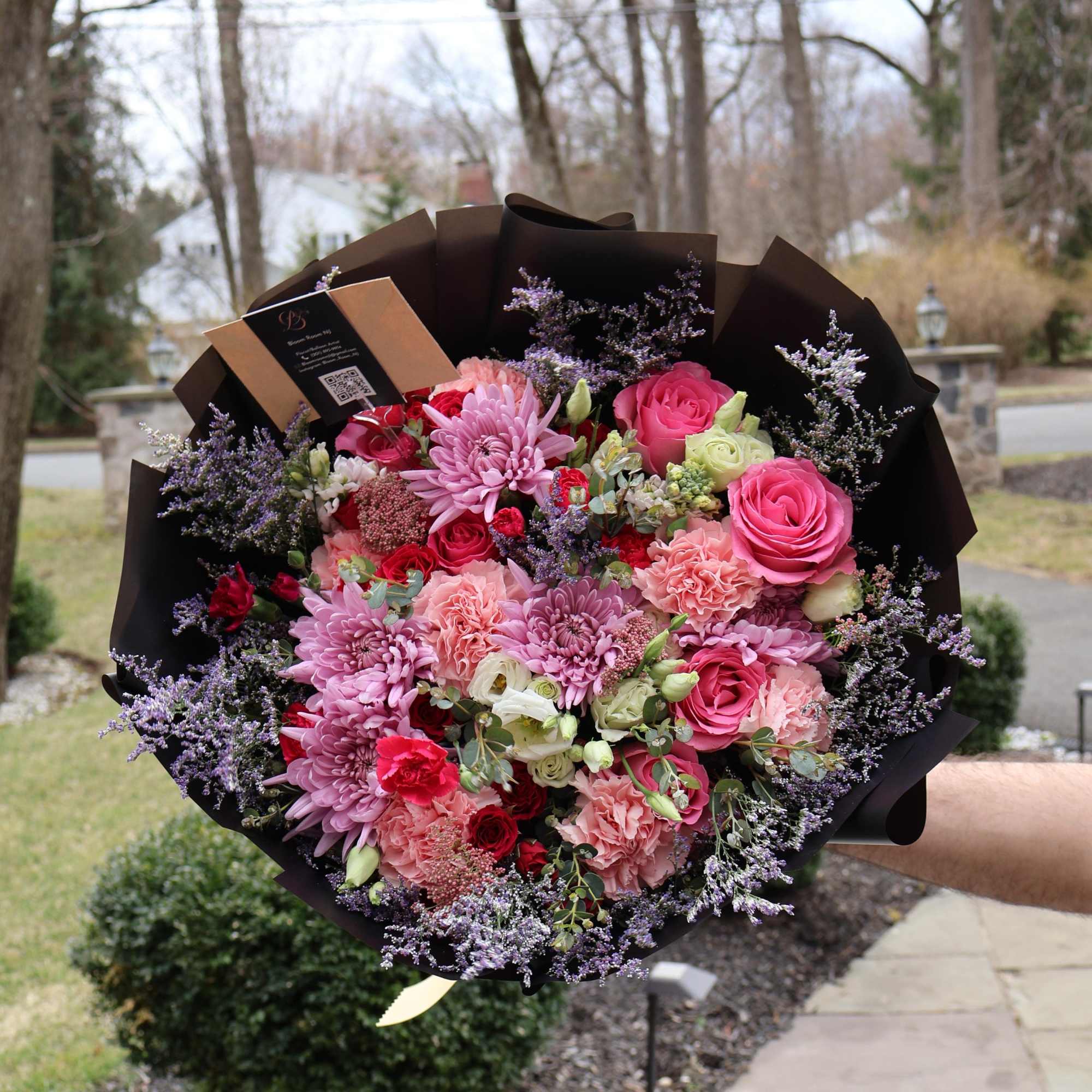 A lush mix of roses, carnations, and chrysanthemums in rich pinks and