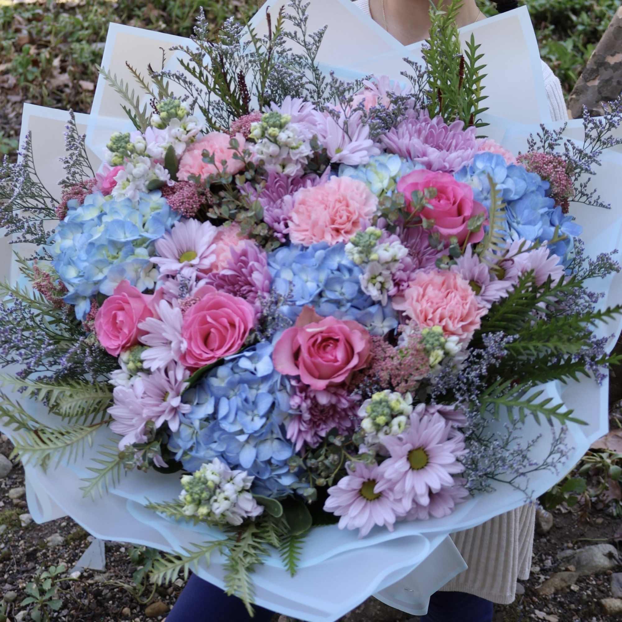 A serene bouquet with soft blue hydrangeas, light pink carnations, and pink