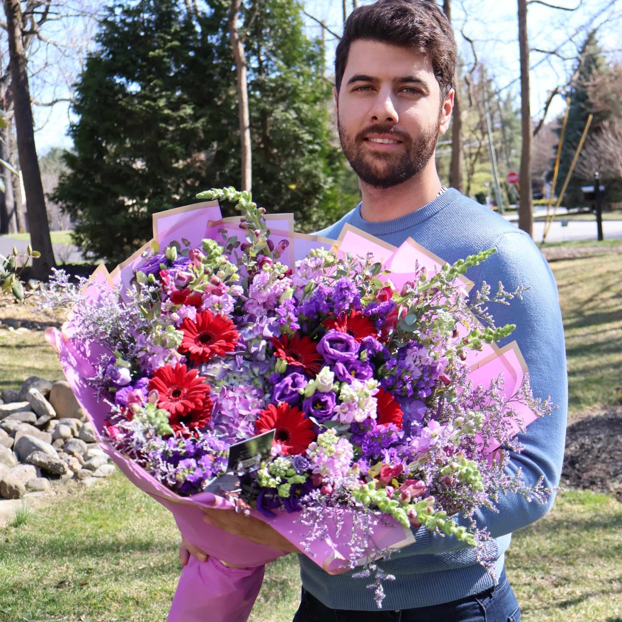 A vibrant bouquet bursting with red gerberas, purple lisianthus, and delicate spring