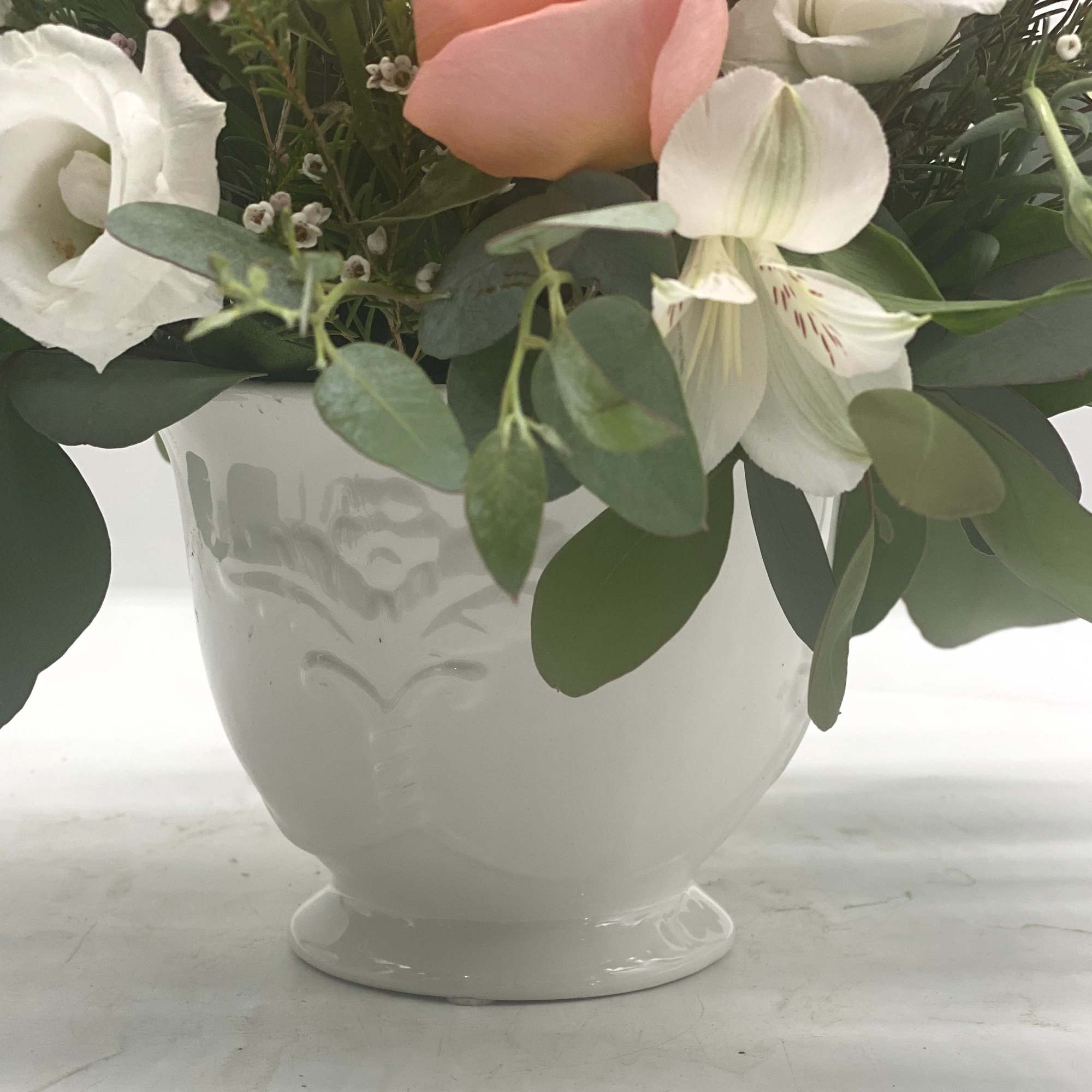 This arrangement features soft coral roses as the focal point, complimented by