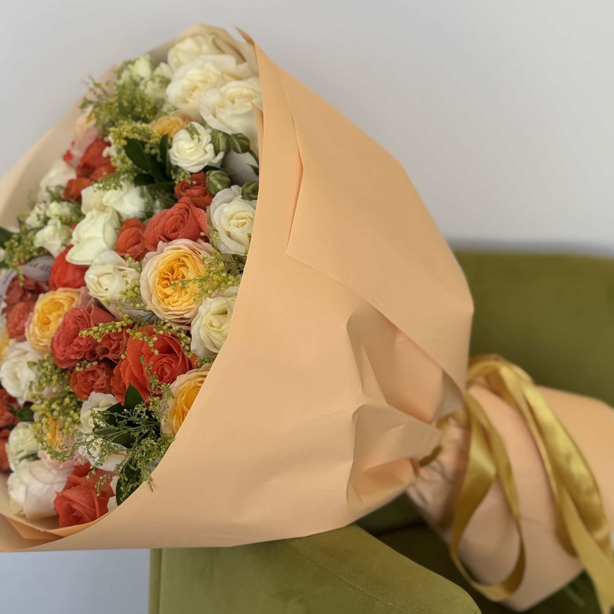 An abundant bouquet of cream, peach, and burnt orange garden roses wrapped
