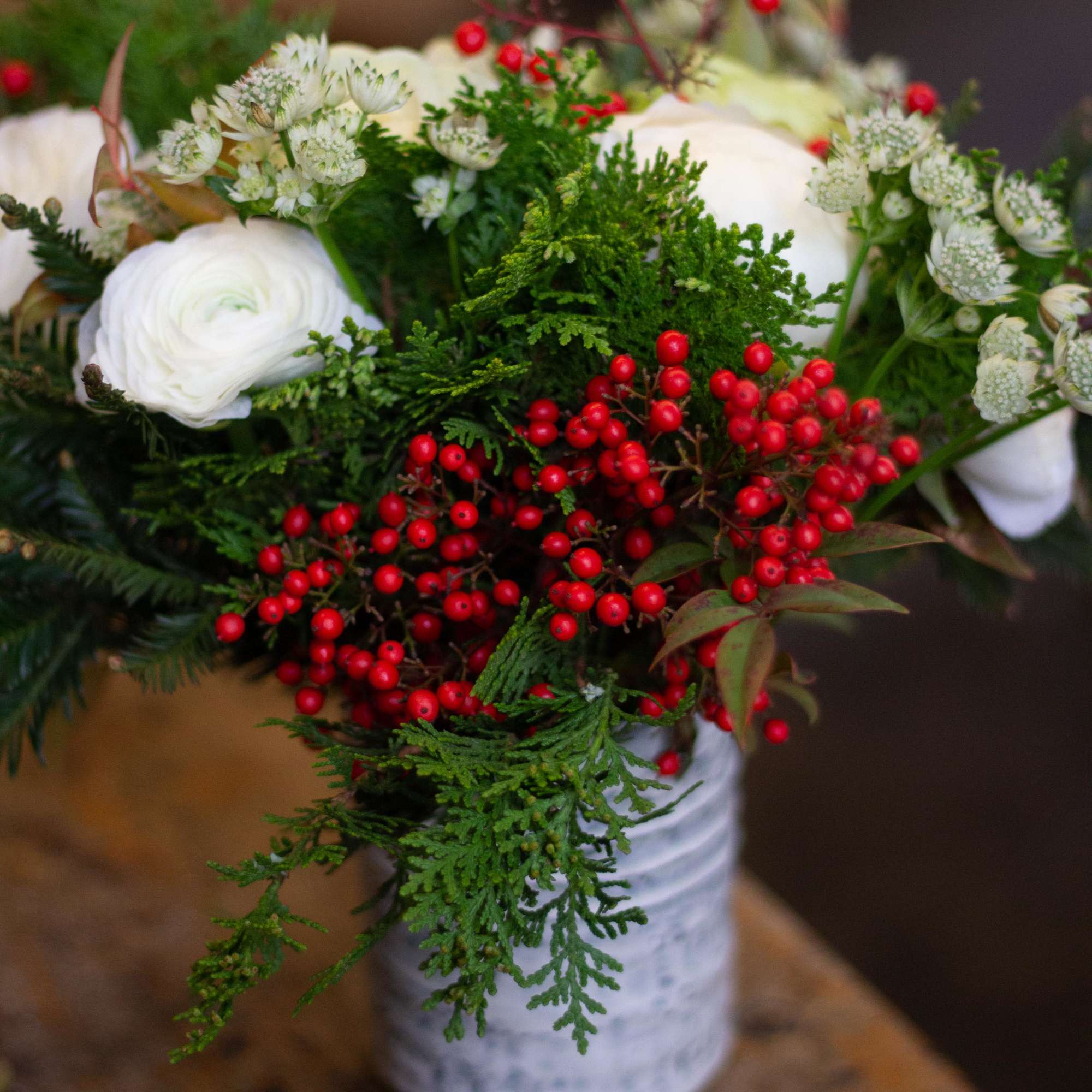 A holiday arrangement that includes a combo of green textures, red flowers A holiday arrangement that includes a combo of green textures, red flowers