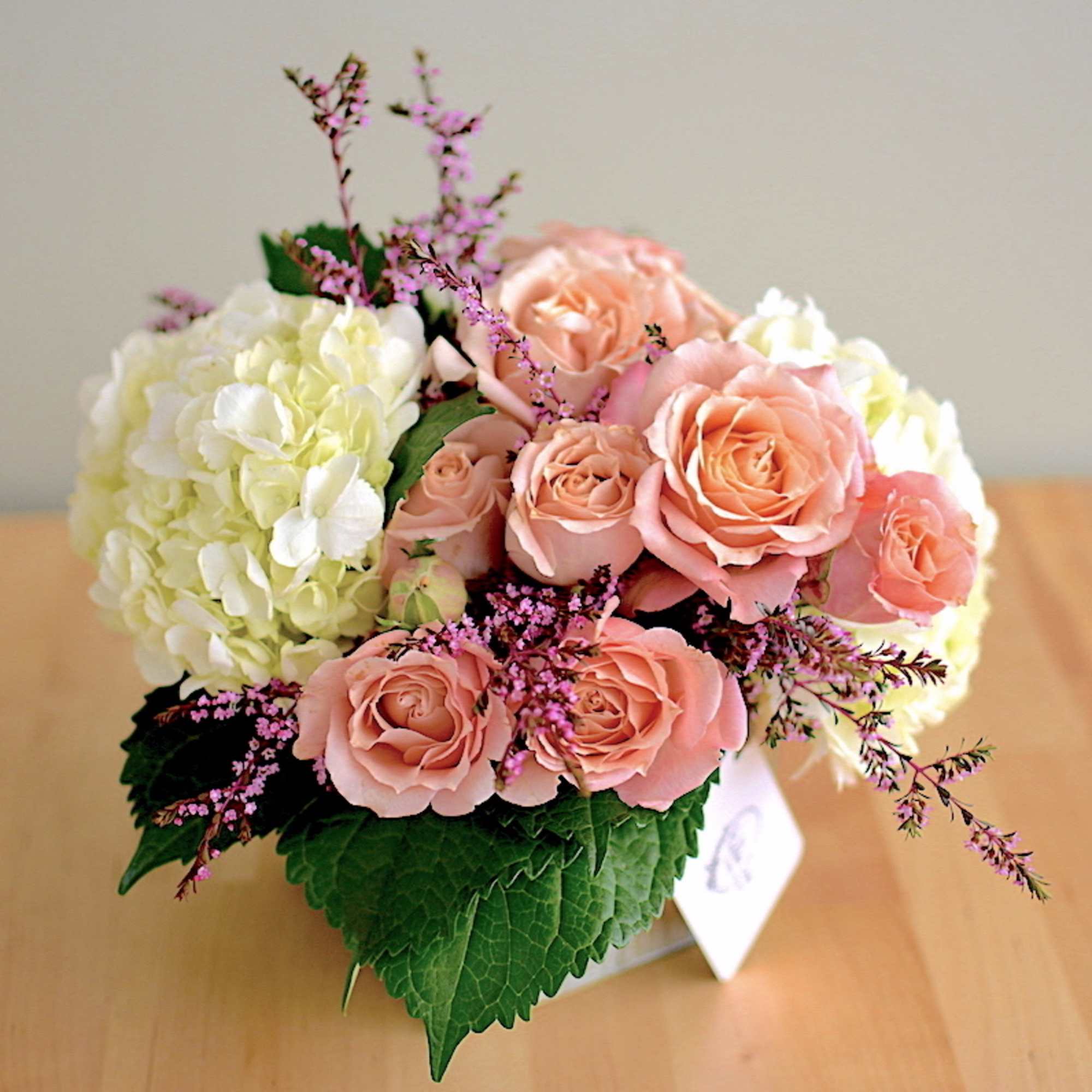 Beautiful spray roses and hydrangeas in an elegant white ceramic container. 