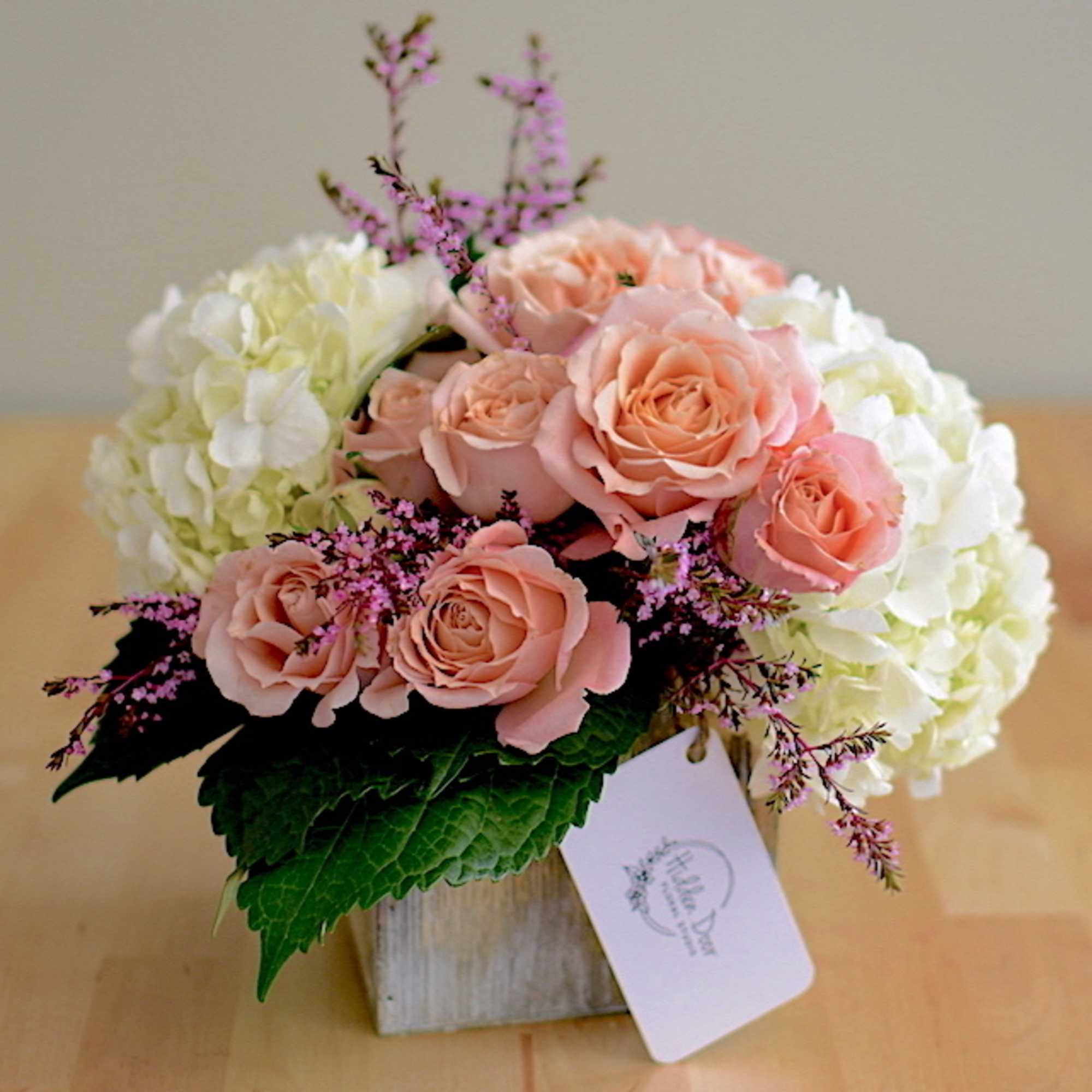 Beautiful spray roses and hydrangeas in an elegant white ceramic container. 