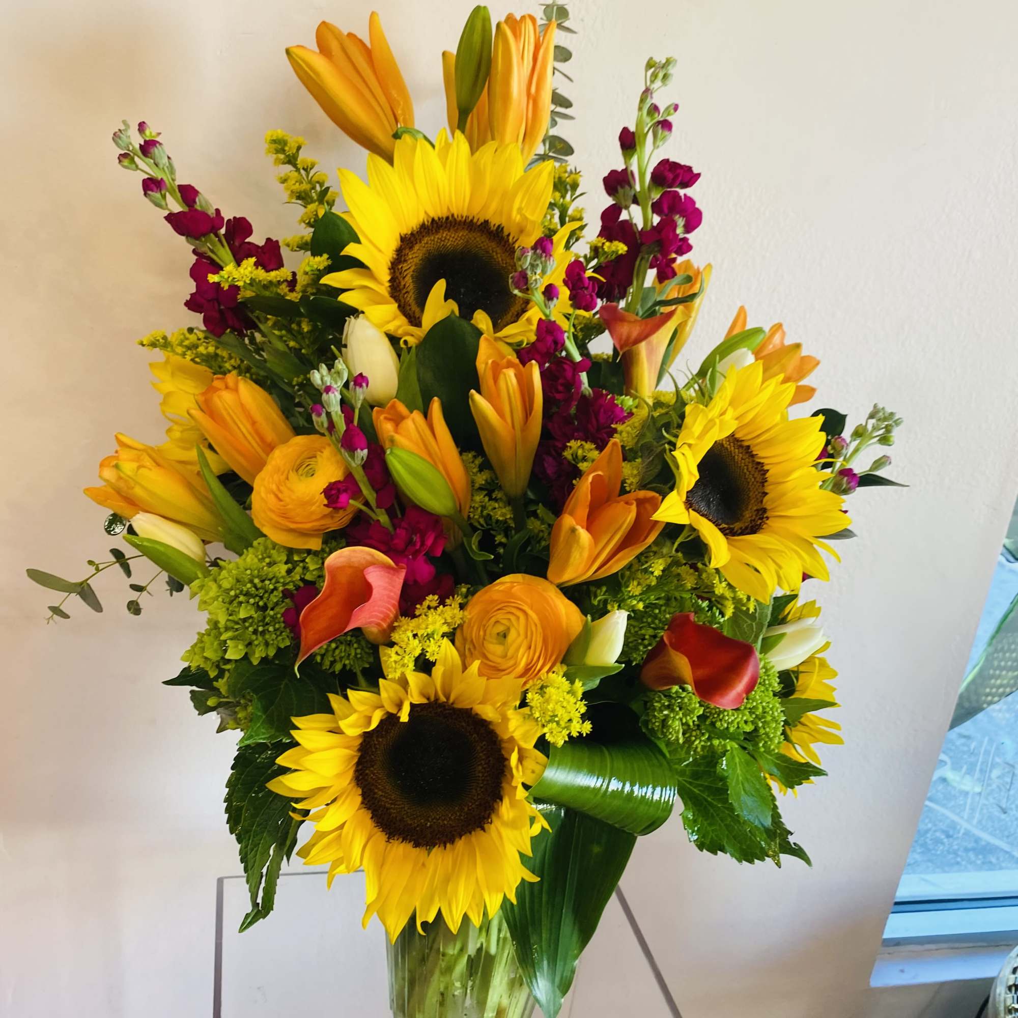 This vibrant floral arrangement features a captivating blend of textures and colors