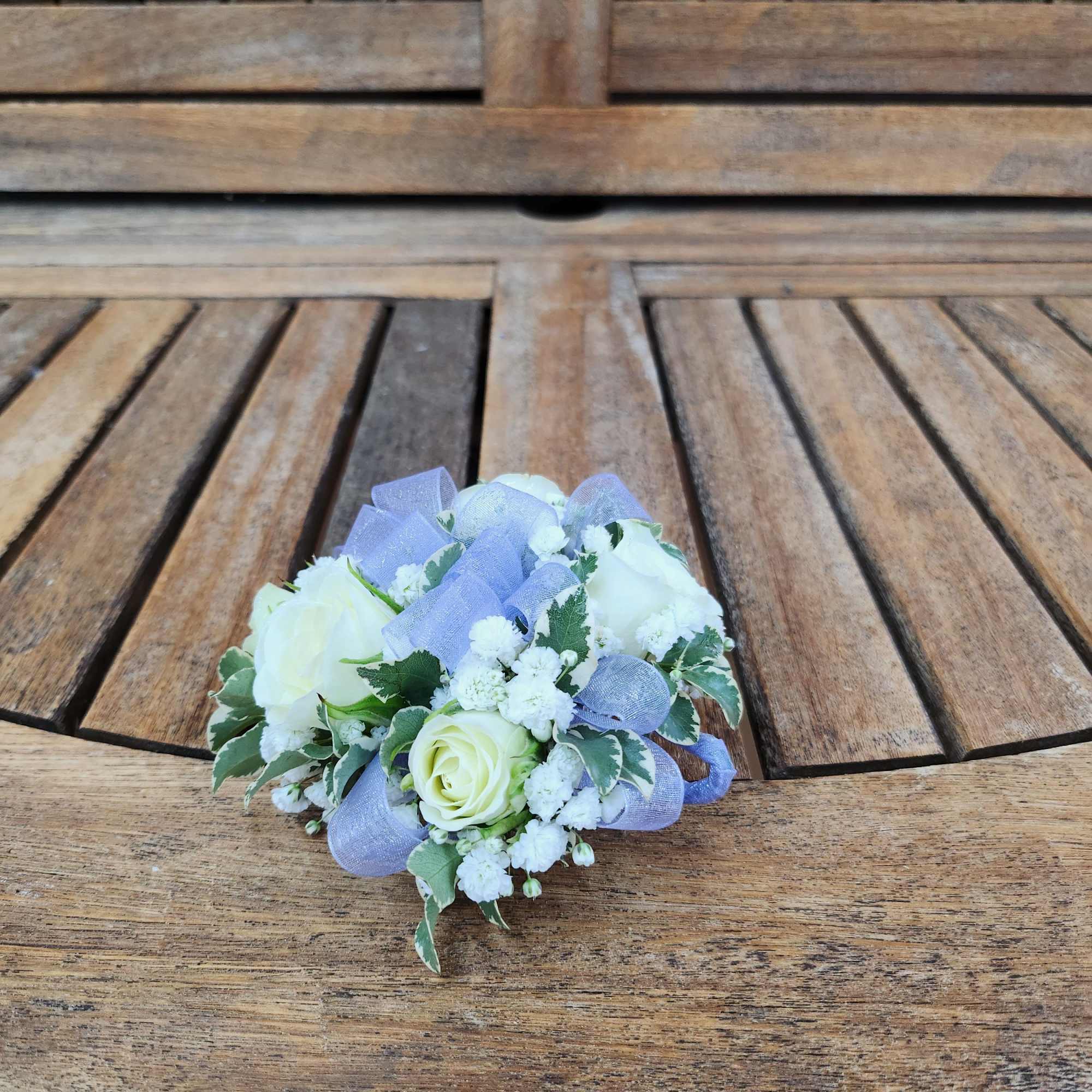 Wrist corsage with white spray roses, filler, greenery and ribbon 