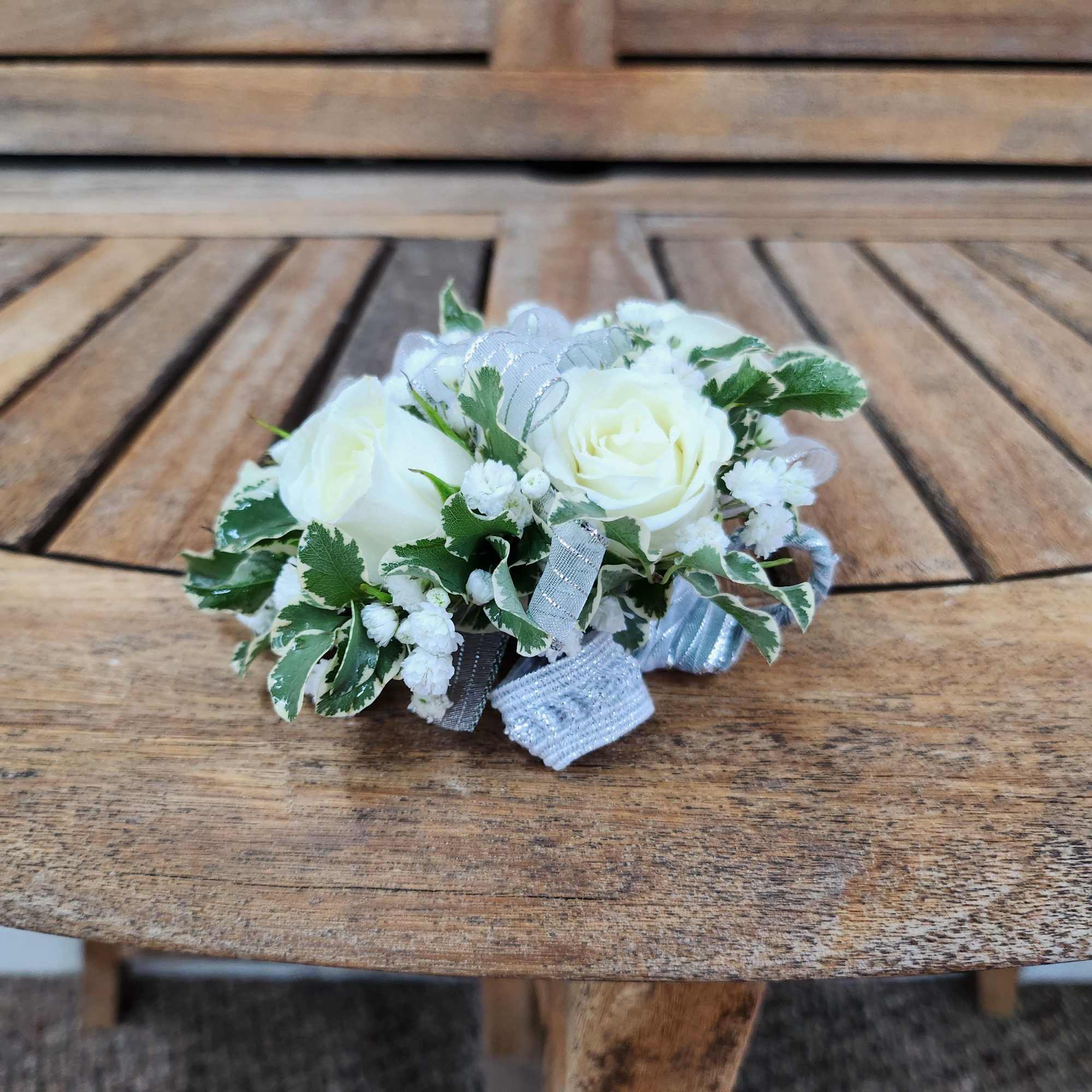 Wrist Corsage with white spray roses, greenery, filler, and silver Ribbon