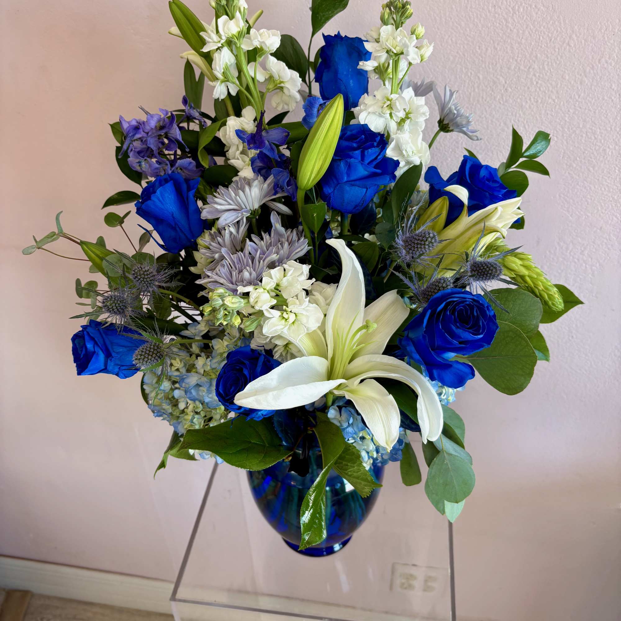 This large vase features 7 blue roses, blue hydrangeas, blue thistle, blue