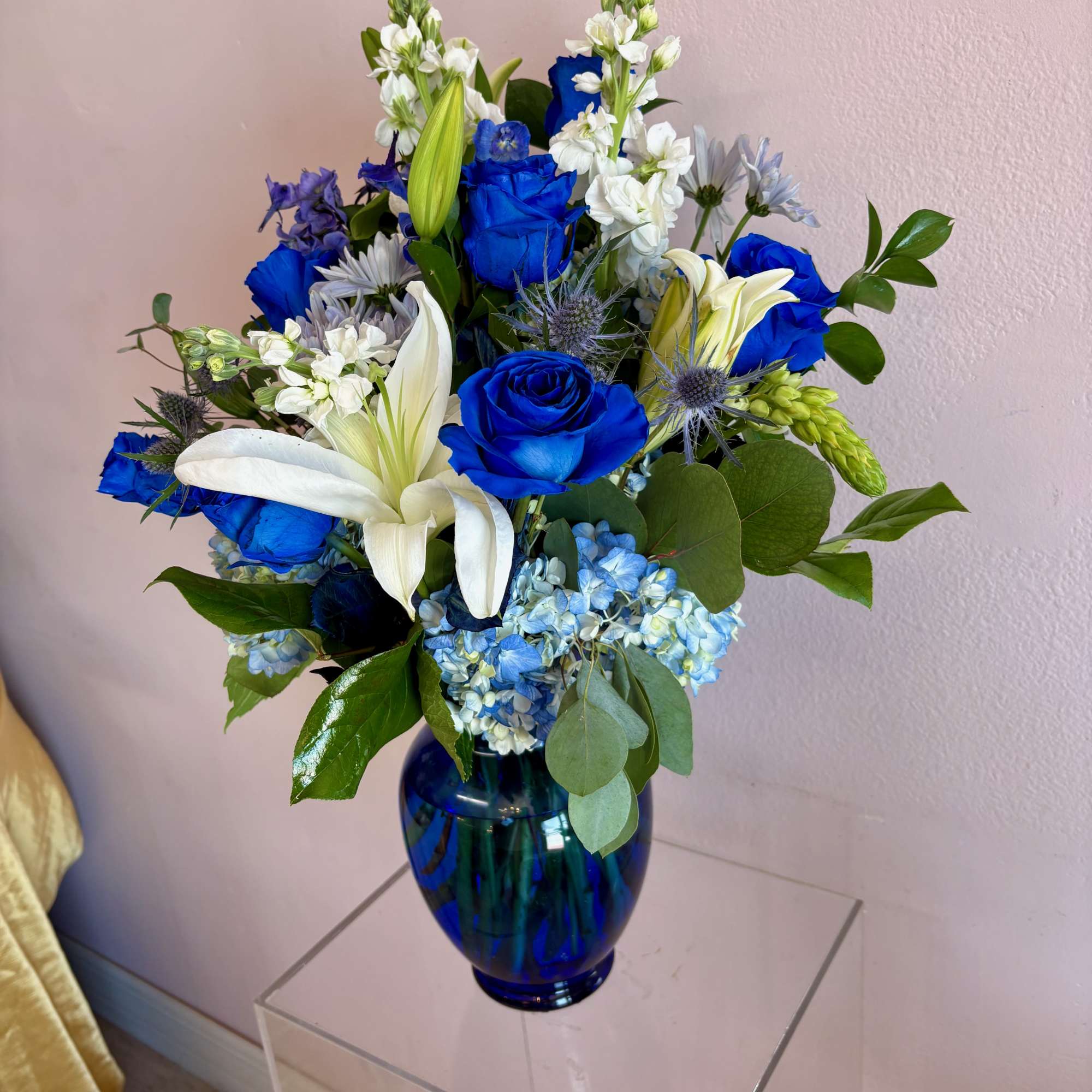 This large vase features 7 blue roses, blue hydrangeas, blue thistle, blue