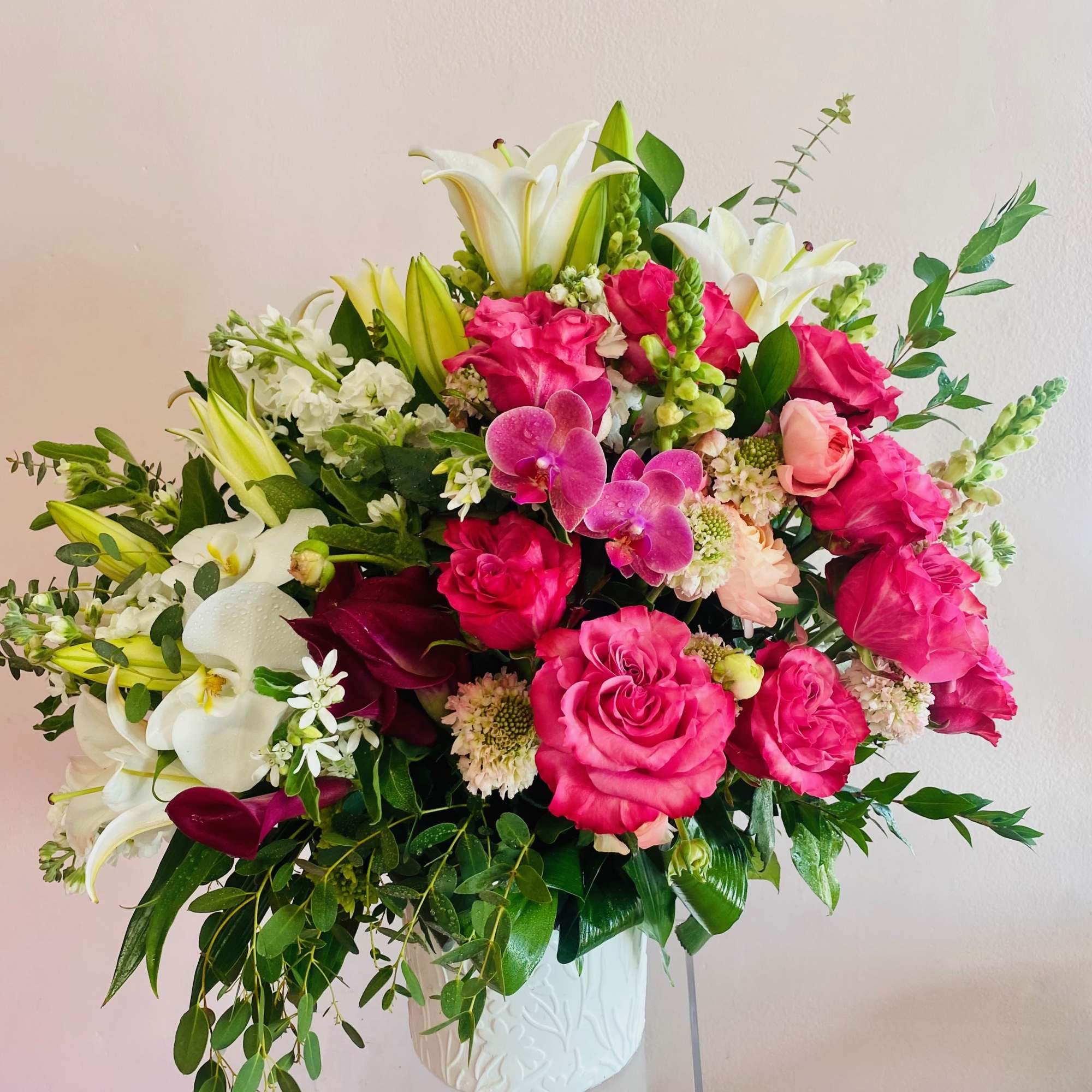 A very feminine arrangement full of blooming hot pink garden roses, burgundy