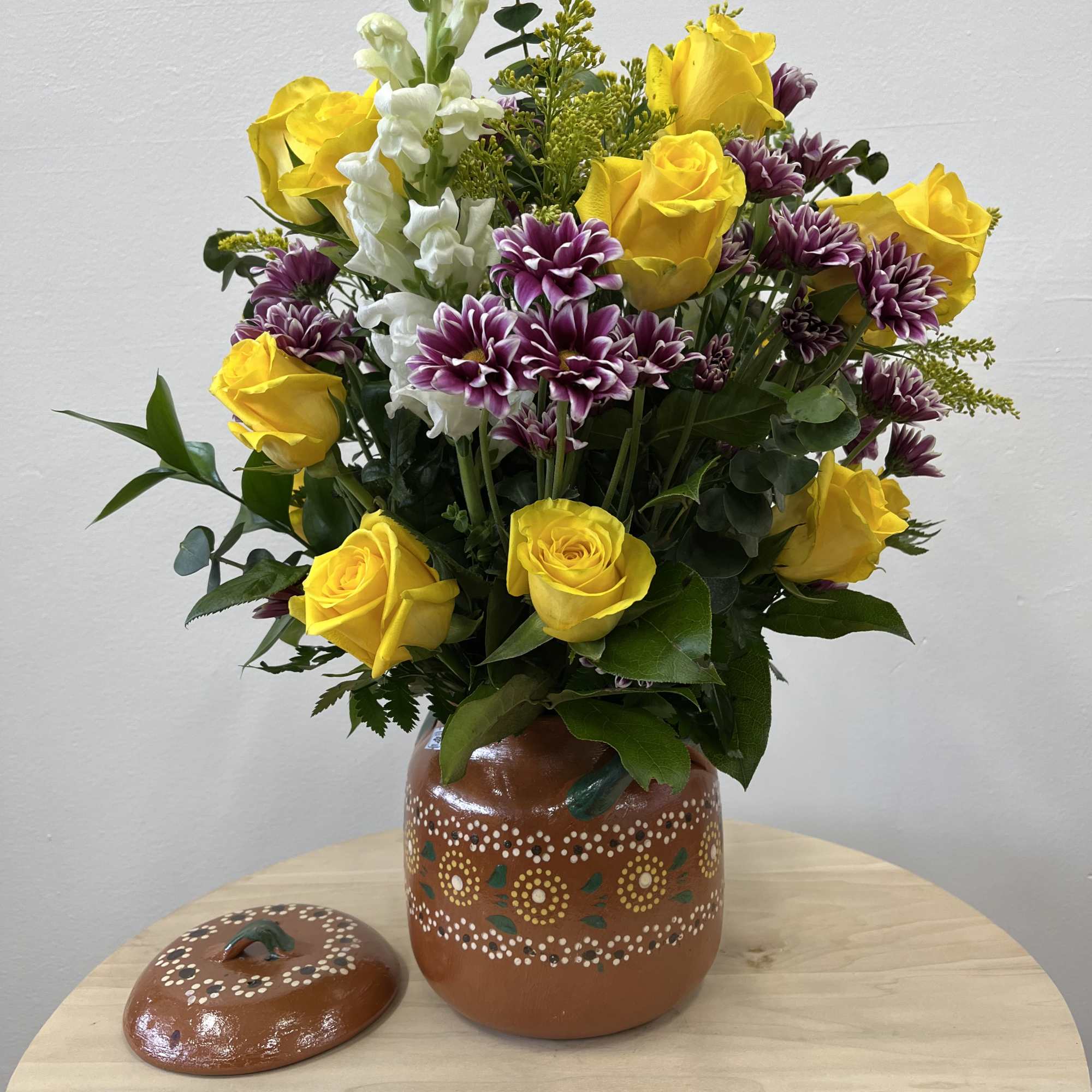A cheerful mix of yellow roses, white stock, and purple daisies in