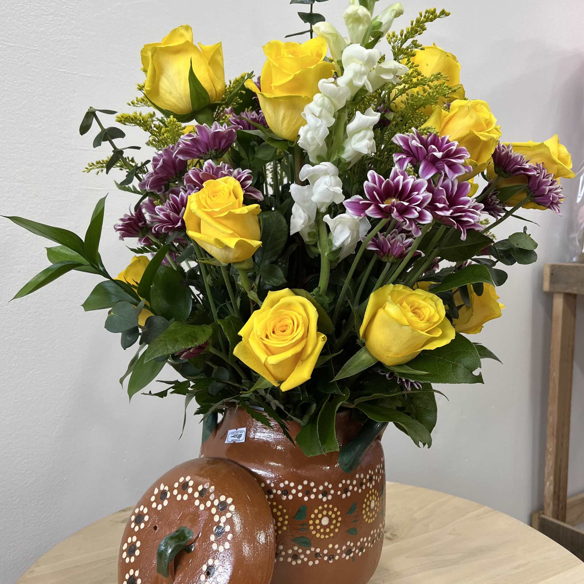 A cheerful mix of yellow roses, white stock, and purple daisies in