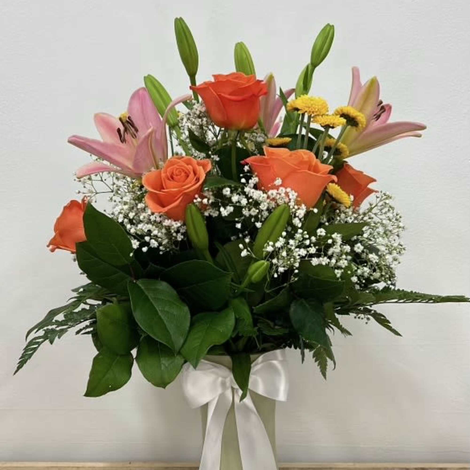 With striking pink lilies and bright orange roses, softened by delicate baby&rsquo;s