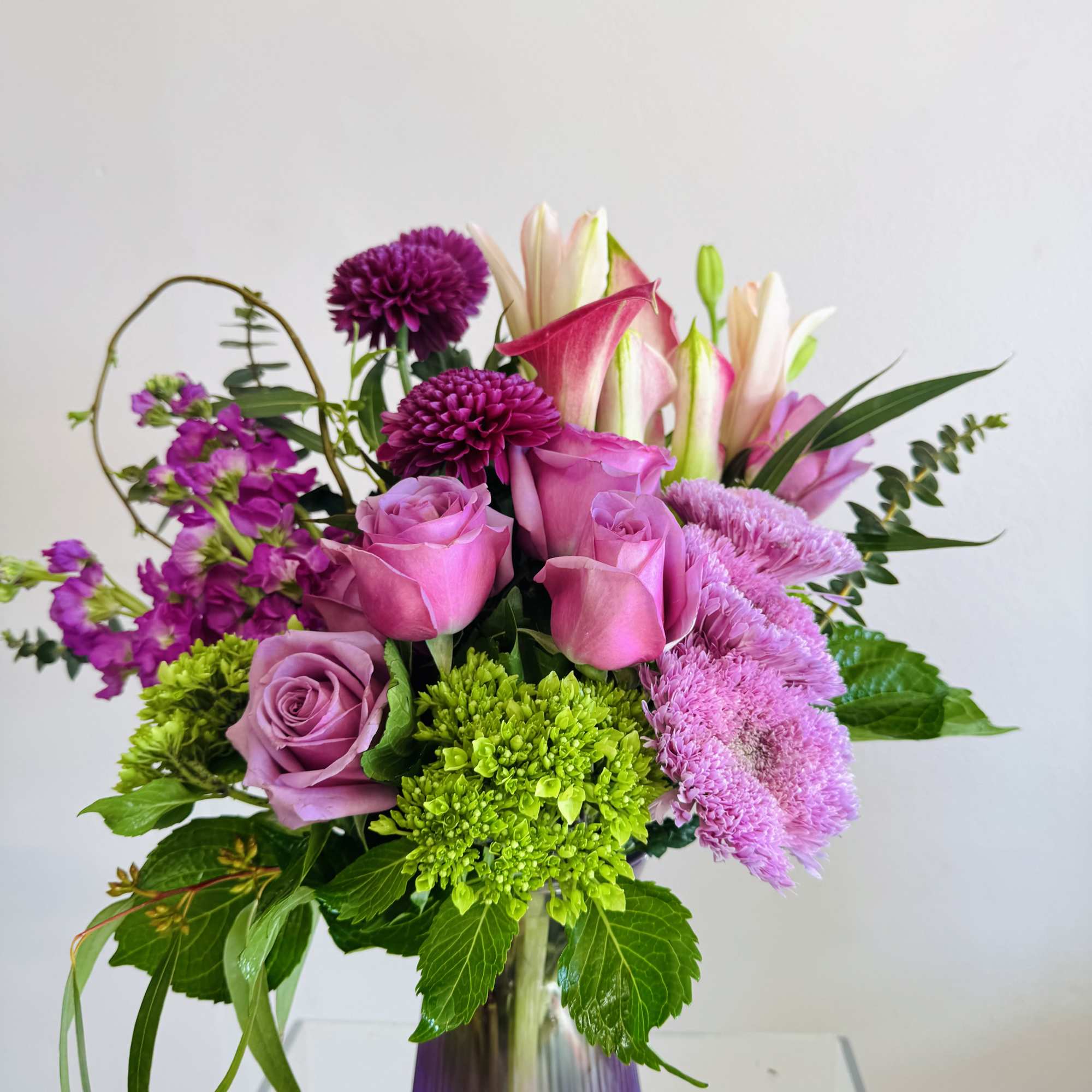A mixed variety of purple florals with an accent of greenery. 