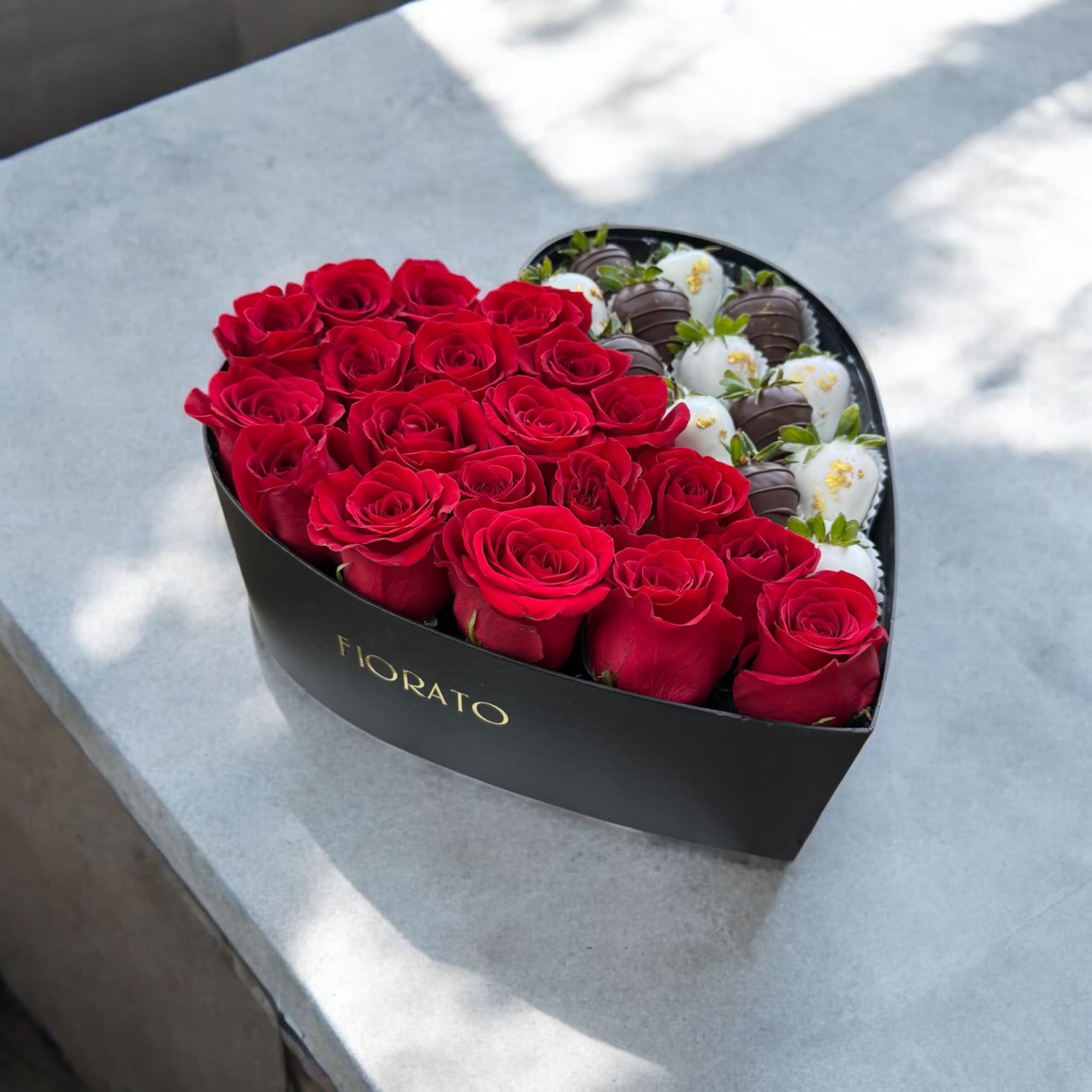 A luxurious black heart-shaped box.
One half filled with 24 bold red roses