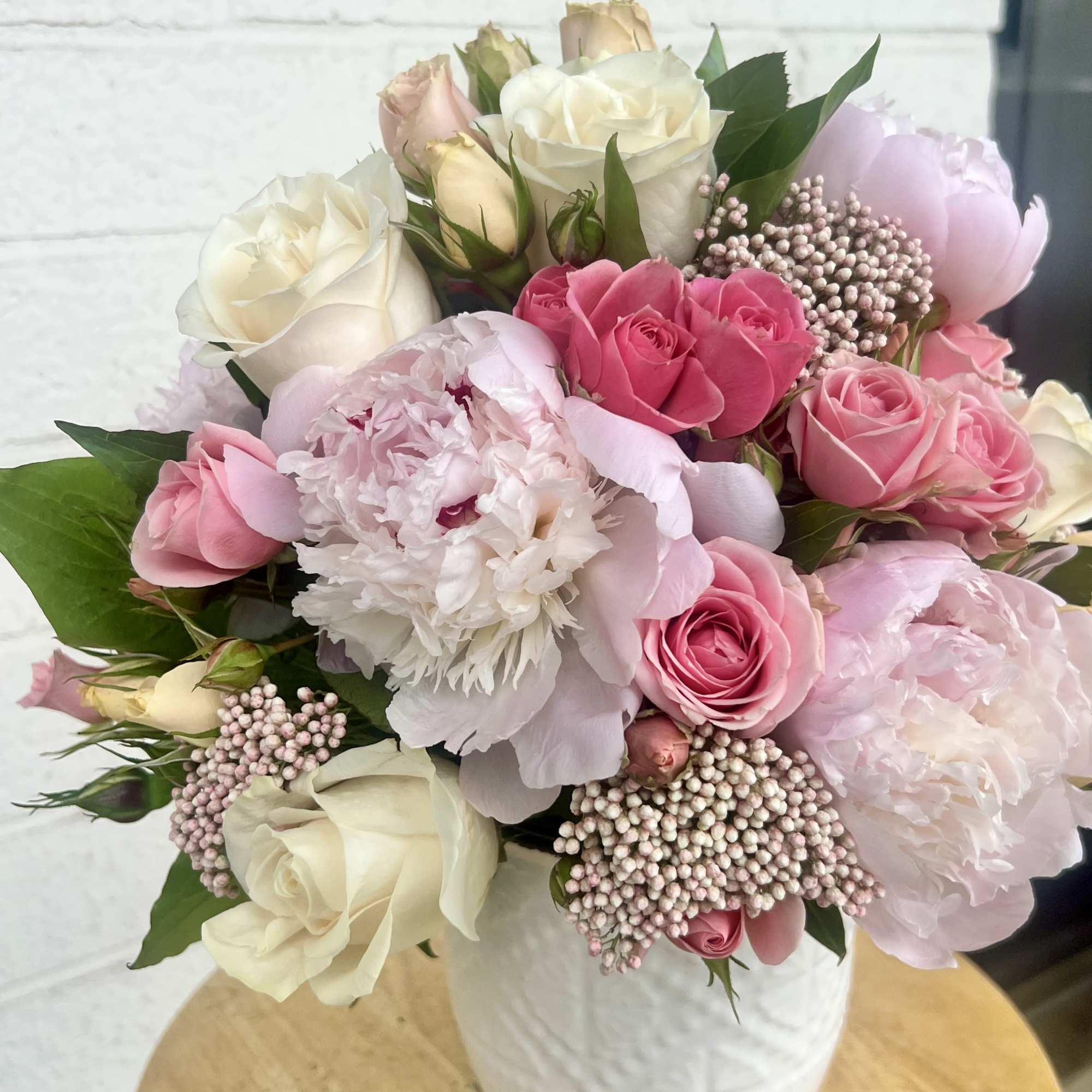 A round bouquet blending delicate peonies and roses with the soft texture