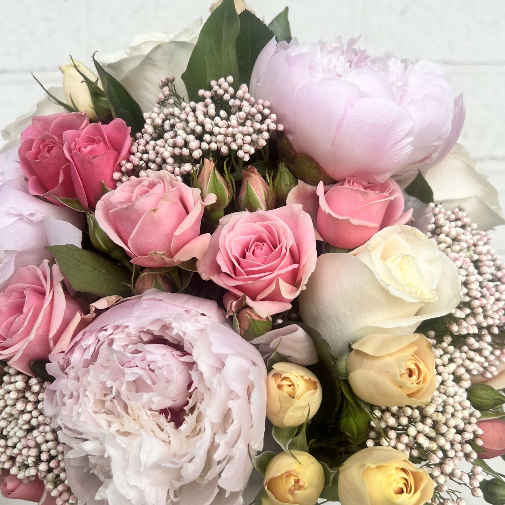 A round bouquet blending delicate peonies and roses with the soft texture
