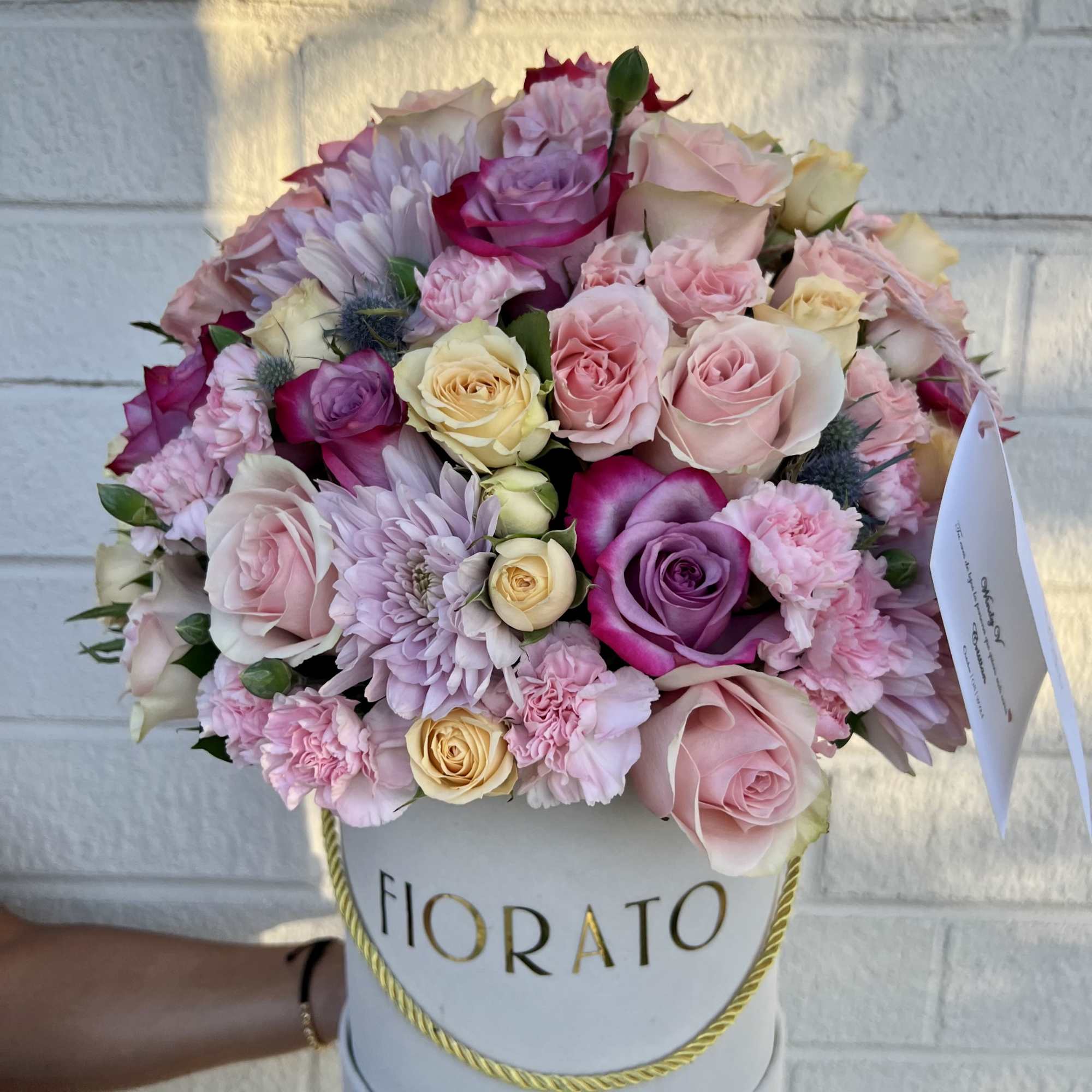 An ethereal and elegant design in a round box, featuring roses in