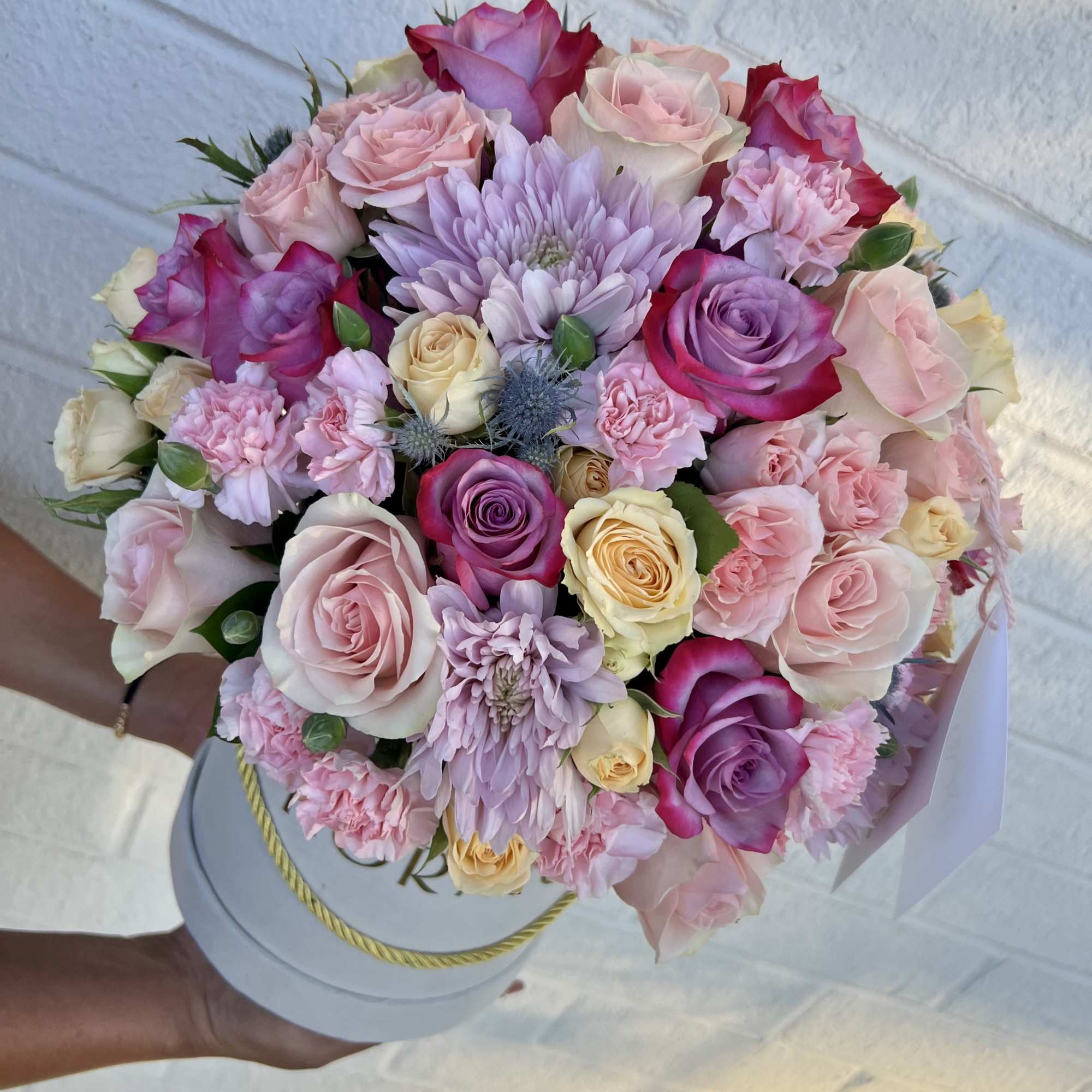 An ethereal and elegant design in a round box, featuring roses in