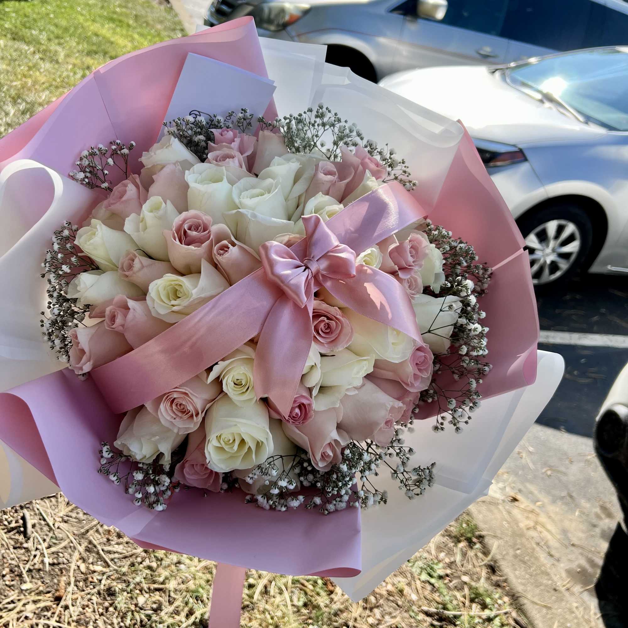 A lush bouquet featuring soft and delicate tones, wrapped in light pink